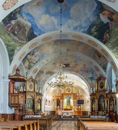 Zdjęcie nr 10: Kościół św. Andrzeja Apostoła w Szaflarach jest murowaną świątynią orientowaną. Składa się z czteroprzęsłowej nawy, przylegającego do niej od wschodu węższego, trójprzęsłowego prezbiterium zamkniętego łukiem spłaszczonym oraz czworobocznej wieży usytuowanej od zachodu. Po bokach nawy, na planie kwadratu ze ściętymi narożami, wzniesiono naprzeciw siebie dwie kaplice boczne, otwarte do wnętrza kościoła półokrągłymi arkadami. Od wschodu do kaplicy Najświętszego Serca Pana Jezusa przylega niewielka kruchta. Z kolei po stronie północnej prezbiterium wzniesiono na planie prostokąta zakrystię, poprzedzoną przedsionkiem i aneksem łączącym ją z kaplicą boczną Matki Boskiej, nad którym znajduje się skarbczyk. Prezbiterium doświetlone zostało przez trzy półokrągłe okna w ścianie południowej. Nawa, opięta na zewnątrz przyporami, została nakryta sklepieniem żaglastym z gurtami, a jej wnętrze, podobnie jak w prezbiterium, rozczłonkowano półfilarami. Zarówno nawę jak i prezbiterium nakryto dachem siodłowym, pokrytym blachą miedzianą. Obie kaplice boczne zasklepiono ośmiodzielnym sklepieniem i przykryto dachem namiotowym, wieńcząc go wielobocznymi latarniami z krzyżem. Doświetlają je półokrągłe okna oraz okulus, umieszczony w ścianie ołtarzowej, zamurowany w kaplicy Najświętszego Serca Pana Jezusa i od zewnątrz wypełniony współczesną mozaiką z wyobrażeniem Chrystusa Pantokratora. Elewacje prezbiterium, nawy i kaplic potynkowano. Od strony zachodniej do nawy przylega dwupoziomowa, czworoboczna wieża. Jej ściany olicowano okładziną z piaskowca. Dolny poziom wieży wyznacza nieznaczny uskok. Tu w przyziemiu urządzono kruchtę, do której prowadzi półokrągły portal. Nad portalem widoczny jest okulus. Górny poziom przepruto z trzech stron półokrągłymi oknami wypełnionymi drewnianymi żaluzjami. Wieżę zwieńczono ostrosłupowym hełmem, pokrytym blachą miedzianą i zakończonym krzyżem, który wspiera się na profilowanym gzymsie koronującym. Zwieńczenie wieży zostało wzbogacone w narożach czterema nadwieszonymi na wspornikach wielobocznymi wieżyczkami z ostrosłupowymi hełmami, pomiędzy którymi z trzech stron umieszczono tarcze zegarowe.
