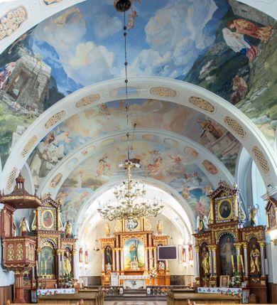 Zdjęcie nr 12: Kościół św. Andrzeja Apostoła w Szaflarach jest murowaną świątynią orientowaną. Składa się z czteroprzęsłowej nawy, przylegającego do niej od wschodu węższego, trójprzęsłowego prezbiterium zamkniętego łukiem spłaszczonym oraz czworobocznej wieży usytuowanej od zachodu. Po bokach nawy, na planie kwadratu ze ściętymi narożami, wzniesiono naprzeciw siebie dwie kaplice boczne, otwarte do wnętrza kościoła półokrągłymi arkadami. Od wschodu do kaplicy Najświętszego Serca Pana Jezusa przylega niewielka kruchta. Z kolei po stronie północnej prezbiterium wzniesiono na planie prostokąta zakrystię, poprzedzoną przedsionkiem i aneksem łączącym ją z kaplicą boczną Matki Boskiej, nad którym znajduje się skarbczyk. Prezbiterium doświetlone zostało przez trzy półokrągłe okna w ścianie południowej. Nawa, opięta na zewnątrz przyporami, została nakryta sklepieniem żaglastym z gurtami, a jej wnętrze, podobnie jak w prezbiterium, rozczłonkowano półfilarami. Zarówno nawę jak i prezbiterium nakryto dachem siodłowym, pokrytym blachą miedzianą. Obie kaplice boczne zasklepiono ośmiodzielnym sklepieniem i przykryto dachem namiotowym, wieńcząc go wielobocznymi latarniami z krzyżem. Doświetlają je półokrągłe okna oraz okulus, umieszczony w ścianie ołtarzowej, zamurowany w kaplicy Najświętszego Serca Pana Jezusa i od zewnątrz wypełniony współczesną mozaiką z wyobrażeniem Chrystusa Pantokratora. Elewacje prezbiterium, nawy i kaplic potynkowano. Od strony zachodniej do nawy przylega dwupoziomowa, czworoboczna wieża. Jej ściany olicowano okładziną z piaskowca. Dolny poziom wieży wyznacza nieznaczny uskok. Tu w przyziemiu urządzono kruchtę, do której prowadzi półokrągły portal. Nad portalem widoczny jest okulus. Górny poziom przepruto z trzech stron półokrągłymi oknami wypełnionymi drewnianymi żaluzjami. Wieżę zwieńczono ostrosłupowym hełmem, pokrytym blachą miedzianą i zakończonym krzyżem, który wspiera się na profilowanym gzymsie koronującym. Zwieńczenie wieży zostało wzbogacone w narożach czterema nadwieszonymi na wspornikach wielobocznymi wieżyczkami z ostrosłupowymi hełmami, pomiędzy którymi z trzech stron umieszczono tarcze zegarowe.