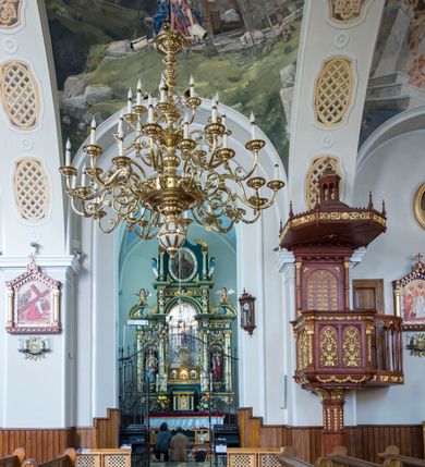 Zdjęcie nr 13: Kościół św. Andrzeja Apostoła w Szaflarach jest murowaną świątynią orientowaną. Składa się z czteroprzęsłowej nawy, przylegającego do niej od wschodu węższego, trójprzęsłowego prezbiterium zamkniętego łukiem spłaszczonym oraz czworobocznej wieży usytuowanej od zachodu. Po bokach nawy, na planie kwadratu ze ściętymi narożami, wzniesiono naprzeciw siebie dwie kaplice boczne, otwarte do wnętrza kościoła półokrągłymi arkadami. Od wschodu do kaplicy Najświętszego Serca Pana Jezusa przylega niewielka kruchta. Z kolei po stronie północnej prezbiterium wzniesiono na planie prostokąta zakrystię, poprzedzoną przedsionkiem i aneksem łączącym ją z kaplicą boczną Matki Boskiej, nad którym znajduje się skarbczyk. Prezbiterium doświetlone zostało przez trzy półokrągłe okna w ścianie południowej. Nawa, opięta na zewnątrz przyporami, została nakryta sklepieniem żaglastym z gurtami, a jej wnętrze, podobnie jak w prezbiterium, rozczłonkowano półfilarami. Zarówno nawę jak i prezbiterium nakryto dachem siodłowym, pokrytym blachą miedzianą. Obie kaplice boczne zasklepiono ośmiodzielnym sklepieniem i przykryto dachem namiotowym, wieńcząc go wielobocznymi latarniami z krzyżem. Doświetlają je półokrągłe okna oraz okulus, umieszczony w ścianie ołtarzowej, zamurowany w kaplicy Najświętszego Serca Pana Jezusa i od zewnątrz wypełniony współczesną mozaiką z wyobrażeniem Chrystusa Pantokratora. Elewacje prezbiterium, nawy i kaplic potynkowano. Od strony zachodniej do nawy przylega dwupoziomowa, czworoboczna wieża. Jej ściany olicowano okładziną z piaskowca. Dolny poziom wieży wyznacza nieznaczny uskok. Tu w przyziemiu urządzono kruchtę, do której prowadzi półokrągły portal. Nad portalem widoczny jest okulus. Górny poziom przepruto z trzech stron półokrągłymi oknami wypełnionymi drewnianymi żaluzjami. Wieżę zwieńczono ostrosłupowym hełmem, pokrytym blachą miedzianą i zakończonym krzyżem, który wspiera się na profilowanym gzymsie koronującym. Zwieńczenie wieży zostało wzbogacone w narożach czterema nadwieszonymi na wspornikach wielobocznymi wieżyczkami z ostrosłupowymi hełmami, pomiędzy którymi z trzech stron umieszczono tarcze zegarowe.