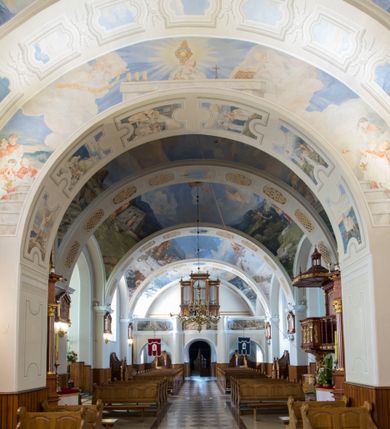 Zdjęcie nr 18: Kościół św. Andrzeja Apostoła w Szaflarach jest murowaną świątynią orientowaną. Składa się z czteroprzęsłowej nawy, przylegającego do niej od wschodu węższego, trójprzęsłowego prezbiterium zamkniętego łukiem spłaszczonym oraz czworobocznej wieży usytuowanej od zachodu. Po bokach nawy, na planie kwadratu ze ściętymi narożami, wzniesiono naprzeciw siebie dwie kaplice boczne, otwarte do wnętrza kościoła półokrągłymi arkadami. Od wschodu do kaplicy Najświętszego Serca Pana Jezusa przylega niewielka kruchta. Z kolei po stronie północnej prezbiterium wzniesiono na planie prostokąta zakrystię, poprzedzoną przedsionkiem i aneksem łączącym ją z kaplicą boczną Matki Boskiej, nad którym znajduje się skarbczyk. Prezbiterium doświetlone zostało przez trzy półokrągłe okna w ścianie południowej. Nawa, opięta na zewnątrz przyporami, została nakryta sklepieniem żaglastym z gurtami, a jej wnętrze, podobnie jak w prezbiterium, rozczłonkowano półfilarami. Zarówno nawę jak i prezbiterium nakryto dachem siodłowym, pokrytym blachą miedzianą. Obie kaplice boczne zasklepiono ośmiodzielnym sklepieniem i przykryto dachem namiotowym, wieńcząc go wielobocznymi latarniami z krzyżem. Doświetlają je półokrągłe okna oraz okulus, umieszczony w ścianie ołtarzowej, zamurowany w kaplicy Najświętszego Serca Pana Jezusa i od zewnątrz wypełniony współczesną mozaiką z wyobrażeniem Chrystusa Pantokratora. Elewacje prezbiterium, nawy i kaplic potynkowano. Od strony zachodniej do nawy przylega dwupoziomowa, czworoboczna wieża. Jej ściany olicowano okładziną z piaskowca. Dolny poziom wieży wyznacza nieznaczny uskok. Tu w przyziemiu urządzono kruchtę, do której prowadzi półokrągły portal. Nad portalem widoczny jest okulus. Górny poziom przepruto z trzech stron półokrągłymi oknami wypełnionymi drewnianymi żaluzjami. Wieżę zwieńczono ostrosłupowym hełmem, pokrytym blachą miedzianą i zakończonym krzyżem, który wspiera się na profilowanym gzymsie koronującym. Zwieńczenie wieży zostało wzbogacone w narożach czterema nadwieszonymi na wspornikach wielobocznymi wieżyczkami z ostrosłupowymi hełmami, pomiędzy którymi z trzech stron umieszczono tarcze zegarowe.