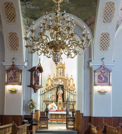 Zdjęcie nr 19: Kościół św. Andrzeja Apostoła w Szaflarach jest murowaną świątynią orientowaną. Składa się z czteroprzęsłowej nawy, przylegającego do niej od wschodu węższego, trójprzęsłowego prezbiterium zamkniętego łukiem spłaszczonym oraz czworobocznej wieży usytuowanej od zachodu. Po bokach nawy, na planie kwadratu ze ściętymi narożami, wzniesiono naprzeciw siebie dwie kaplice boczne, otwarte do wnętrza kościoła półokrągłymi arkadami. Od wschodu do kaplicy Najświętszego Serca Pana Jezusa przylega niewielka kruchta. Z kolei po stronie północnej prezbiterium wzniesiono na planie prostokąta zakrystię, poprzedzoną przedsionkiem i aneksem łączącym ją z kaplicą boczną Matki Boskiej, nad którym znajduje się skarbczyk. Prezbiterium doświetlone zostało przez trzy półokrągłe okna w ścianie południowej. Nawa, opięta na zewnątrz przyporami, została nakryta sklepieniem żaglastym z gurtami, a jej wnętrze, podobnie jak w prezbiterium, rozczłonkowano półfilarami. Zarówno nawę jak i prezbiterium nakryto dachem siodłowym, pokrytym blachą miedzianą. Obie kaplice boczne zasklepiono ośmiodzielnym sklepieniem i przykryto dachem namiotowym, wieńcząc go wielobocznymi latarniami z krzyżem. Doświetlają je półokrągłe okna oraz okulus, umieszczony w ścianie ołtarzowej, zamurowany w kaplicy Najświętszego Serca Pana Jezusa i od zewnątrz wypełniony współczesną mozaiką z wyobrażeniem Chrystusa Pantokratora. Elewacje prezbiterium, nawy i kaplic potynkowano. Od strony zachodniej do nawy przylega dwupoziomowa, czworoboczna wieża. Jej ściany olicowano okładziną z piaskowca. Dolny poziom wieży wyznacza nieznaczny uskok. Tu w przyziemiu urządzono kruchtę, do której prowadzi półokrągły portal. Nad portalem widoczny jest okulus. Górny poziom przepruto z trzech stron półokrągłymi oknami wypełnionymi drewnianymi żaluzjami. Wieżę zwieńczono ostrosłupowym hełmem, pokrytym blachą miedzianą i zakończonym krzyżem, który wspiera się na profilowanym gzymsie koronującym. Zwieńczenie wieży zostało wzbogacone w narożach czterema nadwieszonymi na wspornikach wielobocznymi wieżyczkami z ostrosłupowymi hełmami, pomiędzy którymi z trzech stron umieszczono tarcze zegarowe.