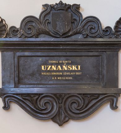 Zdjęcie nr 1: Epitafium w kształcie leżącego prostokąta z wklęsłą płyciną z inskrypcją, wsparte na gzymsie z podwieszonymi pod nim stykającymi się wolutami i zwieńczone wydatnym, profilowanym gzymsem z akroterionami na narożach i gotycką tarczą nakrytą otwartą koroną ujętą stylizowaną wicią roślinną. W tarczy druga tarcza o wciętych pobocznicach i głowicy z rytym godłem herbu Jastrzębiec – odwróconej podkowie z krzyżem kawalerskim. Tarcza nakryta otwartą koroną i klejnotem w postaci jastrzębia z godłem w prawym szponie. Na tablicy inskrypcja „THOMAS AB OLWITA / UZNAŃSKI / HAERES BONORUM SZAFLARY OBIIT / A(NNO) D(OMINI) MD CCCXLVIII.” W prawym dolnym rogu tablicy z inskrypcją sygnatura kamieniarza "E(dward) Stehlik / w Krakowie." 