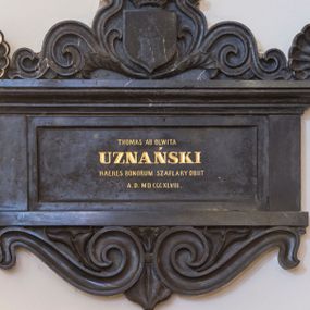 Zdjęcie nr 1: Epitafium w kształcie leżącego prostokąta z wklęsłą płyciną z inskrypcją, wsparte na gzymsie z podwieszonymi pod nim stykającymi się wolutami i zwieńczone wydatnym, profilowanym gzymsem z akroterionami na narożach i gotycką tarczą nakrytą otwartą koroną ujętą stylizowaną wicią roślinną. W tarczy druga tarcza o wciętych pobocznicach i głowicy z rytym godłem herbu Jastrzębiec – odwróconej podkowie z krzyżem kawalerskim. Tarcza nakryta otwartą koroną i klejnotem w postaci jastrzębia z godłem w prawym szponie. Na tablicy inskrypcja „THOMAS AB OLWITA / UZNAŃSKI / HAERES BONORUM SZAFLARY OBIIT / A(NNO) D(OMINI) MD CCCXLVIII.” W prawym dolnym rogu tablicy z inskrypcją sygnatura kamieniarza &quot;E(dward) Stehlik / w Krakowie.&quot; 