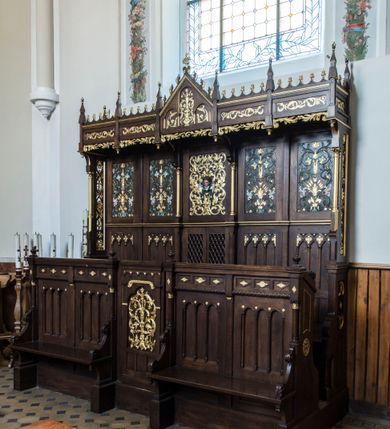 Zdjęcie nr 3: Dębowe, przyścienne stalle uzyskały formę neogotyckiej, pięcioosiowej struktury architektonicznej z zapleckiem i baldachimem. Całość wznosi się na wysokim postumencie. Wejście do nich prowadzi z boków oraz z przodu na osi centralnej, gdzie wprawiono drzwiczki. Ozdobiono je płaskorzeźbioną i złoconą ornamentalną wicią roślinną wpisaną w prostokątną płycinę zwieńczoną stylizowanym trójliściem. Ponad płyciną wprowadzono fryz lombardzki, a poniżej trzy mniejsze, prostokątne, puste płyciny. Na pozostałych osiach na przedpiersiu usytuowano cztery płyciny, które stanowią zaplecek dla dwóch ławek flankujących wejście środkowe. Ławki ujmują wolutowe boki, zdobione stylizowanymi liśćmi akantu, przechodzące poniżej na dekoracyjne wsporniki ustawione na wysokich cokolikach. Jednocześnie wolutowe boki przylegają do wysokich postumentów, na których ustawiono kolumienki o złoconych kapitelach korynckich, podtrzymujących wyłamane belkowanie, stanowiące jednocześnie parapet stalli. Każdą z dolnych płycin zdobi triada półokrągłych arkadek wspartych na smukłych kolumienkach ustawionych na cokole. Także belkowanie artykułują triady płycin ozdobione złoconymi i płaskorzeźbionymi motywami kwiatowymi w romboidalnych obramieniach. Również zaplecek stali uzyskał pięcioosiową artykulację wyznaczoną przez płyciny ułożone w dwóch poziomach. W dolnym poziomie użyto płycin dekorowanych triadami trójkątnych arkadek na smukłych filarkach, które w górnej części tworzą dekoracyjną, romboidalną kratownicę z wpisanym złoconym ornamentem roślinnym. Tą rytmikę przerywa pole osi środkowej, gdzie wprawiono dwuskrzydłowe drzwiczki z ażurową romboidalną kratką. W górnym poziomie wprawiono prostokątne płyciny ozdobione płaskorzeźbioną, polichromowaną i złoconą dekoracją floralno-roślinną, gdzie można wyróżnić złote kłosy zbóż, stylizowane kwiaty lilii górskich i szarotek. Płycinę na osi środkowej  zdobi bujny, płaskorzeźbiony i złocony ornament roślinny, w którego środku widoczna jest uskrzydlona główka aniołka. Jego srebrzone skrzydła przewiązane są zieloną stułą kapłańską. Po bokach płycinę flankują dwie złocone kolumienki o korynckich kapitelach na niskich cokolikach, podtrzymujące wysokie imposty, na które spływają wolutowe konsole. Wspierają one trójkątny przyczółek rozdzielający na dwie części baldachim stalli. Dekoracyjny baldachim wspiera się na wąskich bokach zdobionych od przodu smukłymi, złoconymi kolumienkami o korynckich kapitelach na wysokich postumentach. Za kolumienkami znajdują się płyciny wypełnione ażurowym, złoconym ornamentem roślinnym. Pięcioosiowy podział baldachimu odpowiada artykulacji zaplecka oraz przedpiersi stalli. Tworzy go wypiętrzony trójkątny przyczółek zdobiony czołgankami i kwiatonem oraz cztery prostokątne, wąskie płyciny rozdzielone stylizowanymi pinaklami. Pomiędzy nimi u góry rozciąga się odwrócona arkatura, a u dołu ażurowy, złocony ornament roślinny. Pole przyczółka dekoruje triada półokrągłych płycin. Wpisano w nie stylizowane kwiaty w wazonie. Podłużne płyciny w skrajnych osiach zdobione są złoconą i płaskorzeźbioną wicią roślinną.           