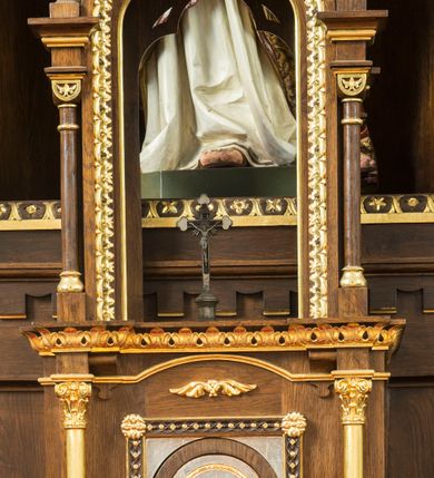Zdjęcie nr 4: Przyścienny trójosiowy, jednokondygnacyjny ołtarz architektoniczny ustawiono na dwustopniowym podeście. Stipes ołtarzowy flankowany przez dwie złocone kolumienki wspierające mensę, ozdobiono trzema płycinami zamkniętymi łukiem odcinkowym. Pola skrajne płycin wypełnia romboidalny czworobok wpisany w owal. Jego wnętrze dekoruje ornamentyka geometryczno-roślinna. Pole środkowe ozdobiono kwadratem wpisanym w owal, w środku którego umieszczono krzyż równoramienny w promienistym otoku. Na mensie ustawiono czworoboczne tabernakulum zwieńczone baldachimem. Front tabernakulum flankują dwie, smukłe, złocone kolumienki o korynckich kapitelach podtrzymujące spłaszczony łuk odcinkowy. Srebrzone półokrągłe drzwiczki wpisano w prostokątne obramienie dekorowane w narożach złoconymi rozetkami. Na drzwiczkach umieszczono chrystogram "IHS" ponad kłosami i winnym gronem. Baldachim tabernakulum uzyskał formę ażurowej, czworobocznej kapliczki o półkoliście zamkniętych, prostokątnych ściankach z wpisanym w górnej części trójliściem. W jej narożach umieszczono kolumienki na wysokich postumentach z kapitelami kostkowymi. Trójosiowe retabulum wsparto na wysokim postumencie, flankowanym przez nieznacznie wysunięte smukłe podpory, dekorowane od frontu płaskorzeźbionym ornamentem roślinnym. Na nich wspierają się skrajne kolumienki, zamykające partię cokołową nastawy. Artykułują je dwie edikule w skrajnych osiach zamknięte łukiem odcinkowym, ozdobionym płaskorzeźbionym ornamentem roślinnym. Wnętrze edikul wypełnia złocona kratownica z polami zdobionymi motywem stylizowanego krzyżyka. Ponad nimi widoczny jest fryz arkadkowy. Na osi środkowej umieszczono prostokątną, półkoliście zamknietą wnękę o konsze dekorowanej stylizowanymi kasetonami. W niej ustawiono stojacą figurę Najświętszego Serca Pana Jezusa. Wnękę flankują dwie złocone kolumny o kapitelach kostkowych i trzonach zdobionych pierścieniami. Podtrzymują one nadbudowę ze zwieńczeniem zakończonym latarnią. Nadbudowę u góry zamknięto nadwieszonym łukiem odcinkowym. Po bokach flankują ją dwie złocone kolumienki o korynckich kapitelach. Pomiędzy kolumnami widoczny jest fryz arkadowy z umieszczoną na środku złoconą rozetą. Łuk w górnej partii udekorowano złoconą koronką oraz znajdującymi się po bokach dwiema, wielobocznymi sterczynami. Zwieńczenie uzyskało kształt płaskiej kapliczki o dwuspadowym dachu z prostokątnym, półkoliście zamkniętym polem środkowym flankowanym parą kolumienek. Pole dekorowane arkaturą wypełnia obraz "Powrót syna Marnotrawnego". Na dachu kapliczki ustawiono na osi ażurową latarnię a po jej bokach wieloboczne sterczyny. Ponad skrajnymi edikulami w osiach bocznych w partii cokołowej usytuowano płyciny zamknięte po bokach złoconymi kolumienkami z kapitelami kostkowymi, o trzonach dekorowanych pierścieniami, podtrzymujące trójkątne, nadwieszone przyczółki. Zdobi je złocona koronka oraz motyw fryzu arkadkowego. Nad przyczółkami ustawiono zwieńczenie w formie płaskiej kapliczki o półkoliście zamkniętym, ażurowym wykroju wypełnionym złoconym, ornamentem roślinnym z latarenką. Prostokątne płyciny dekorowane w górnej części stylizowanym maswerkiem zawierają płaskorzeźbione przedstawienia. Z lewej strony wyobrażono Chrystusa jako Dobrego Pasterza, a z prawej cudowne rozmnożenie chleba.             