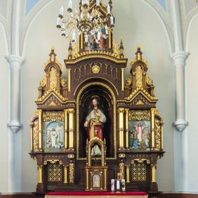 Zdjęcie nr 1: Przyścienny trójosiowy, jednokondygnacyjny ołtarz architektoniczny ustawiono na dwustopniowym podeście. Stipes ołtarzowy flankowany przez dwie złocone kolumienki wspierające mensę, ozdobiono trzema płycinami zamkniętymi łukiem odcinkowym. Pola skrajne płycin wypełnia romboidalny czworobok wpisany w owal. Jego wnętrze dekoruje ornamentyka geometryczno-roślinna. Pole środkowe ozdobiono kwadratem wpisanym w owal, w środku którego umieszczono krzyż równoramienny w promienistym otoku. Na mensie ustawiono czworoboczne tabernakulum zwieńczone baldachimem. Front tabernakulum flankują dwie, smukłe, złocone kolumienki o korynckich kapitelach podtrzymujące spłaszczony łuk odcinkowy. Srebrzone półokrągłe drzwiczki wpisano w prostokątne obramienie dekorowane w narożach złoconymi rozetkami. Na drzwiczkach umieszczono chrystogram "IHS" ponad kłosami i winnym gronem. Baldachim tabernakulum uzyskał formę ażurowej, czworobocznej kapliczki o półkoliście zamkniętych, prostokątnych ściankach z wpisanym w górnej części trójliściem. W jej narożach umieszczono kolumienki na wysokich postumentach z kapitelami kostkowymi. Trójosiowe retabulum wsparto na wysokim postumencie, flankowanym przez nieznacznie wysunięte smukłe podpory, dekorowane od frontu płaskorzeźbionym ornamentem roślinnym. Na nich wspierają się skrajne kolumienki, zamykające partię cokołową nastawy. Artykułują je dwie edikule w skrajnych osiach zamknięte łukiem odcinkowym, ozdobionym płaskorzeźbionym ornamentem roślinnym. Wnętrze edikul wypełnia złocona kratownica z polami zdobionymi motywem stylizowanego krzyżyka. Ponad nimi widoczny jest fryz arkadkowy. Na osi środkowej umieszczono prostokątną, półkoliście zamknietą wnękę o konsze dekorowanej stylizowanymi kasetonami. W niej ustawiono stojacą figurę Najświętszego Serca Pana Jezusa. Wnękę flankują dwie złocone kolumny o kapitelach kostkowych i trzonach zdobionych pierścieniami. Podtrzymują one nadbudowę ze zwieńczeniem zakończonym latarnią. Nadbudowę u góry zamknięto nadwieszonym łukiem odcinkowym. Po bokach flankują ją dwie złocone kolumienki o korynckich kapitelach. Pomiędzy kolumnami widoczny jest fryz arkadowy z umieszczoną na środku złoconą rozetą. Łuk w górnej partii udekorowano złoconą koronką oraz znajdującymi się po bokach dwiema, wielobocznymi sterczynami. Zwieńczenie uzyskało kształt płaskiej kapliczki o dwuspadowym dachu z prostokątnym, półkoliście zamkniętym polem środkowym flankowanym parą kolumienek. Pole dekorowane arkaturą wypełnia obraz "Powrót syna Marnotrawnego". Na dachu kapliczki ustawiono na osi ażurową latarnię a po jej bokach wieloboczne sterczyny. Ponad skrajnymi edikulami w osiach bocznych w partii cokołowej usytuowano płyciny zamknięte po bokach złoconymi kolumienkami z kapitelami kostkowymi, o trzonach dekorowanych pierścieniami, podtrzymujące trójkątne, nadwieszone przyczółki. Zdobi je złocona koronka oraz motyw fryzu arkadkowego. Nad przyczółkami ustawiono zwieńczenie w formie płaskiej kapliczki o półkoliście zamkniętym, ażurowym wykroju wypełnionym złoconym, ornamentem roślinnym z latarenką. Prostokątne płyciny dekorowane w górnej części stylizowanym maswerkiem zawierają płaskorzeźbione przedstawienia. Z lewej strony wyobrażono Chrystusa jako Dobrego Pasterza, a z prawej cudowne rozmnożenie chleba.             