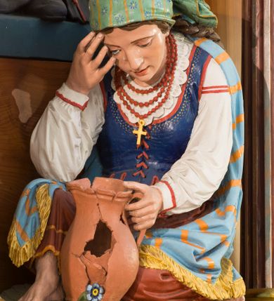 Zdjęcie nr 10: Przyścienną nastawę architektoniczną, trójosiową wykonano z drewna modrzewiowego. Jest to konstrukcja jednokondygnacyjna ze zwieńczeniem, w formie łuku triumfalnego, ustawiona na dwustrefowym cokole. Oś środkową wydzielają dwie pary kolumn o kapitelach kompozytowych i kanelowanych trzonach dźwigających wydłużone imposty. Kolumny wewnętrzne zostały połączone nad polem środkowym fryzem i gzymsem. Z kolei kolumny zewnętrze podtrzymują belkowanie zwieńczenia. Pole środkowe wypełnia nisza w formie stojącego prostokąta zamkniętego łukiem półkolistym z arkaturą z obrazem św. Andrzeja Apostoła. W osiach zewnętrznych usytuowano niższe flankowane parą kanelowanych kolumn z kapitelami kompozytowymi podtrzymujących imposty połączone nad polem fryzem i gzymsem. Nisze uzyskały kształt stojącego prostokąta zamkniętego łukiem półkolistym z arkaturą z figurami św. Wincentego a Paulo i św. Jana Kantego. Ponad niszami na belkowaniu usytuowano cokoły z figurami aniołów trzymających insygnia królewskie. Zwieńczenie uzyskało kształt leżącego prostokąta flankowanego dwiema parami złoconych kolumienek, dźwigających imposty i gzyms nad polem środkowym wyłamanym w trójkąt. Po bokach widoczne są spływy wolutowe. W polu znajduje się rama w formie kwadratu z wpisanym kołem z płaskorzeźbionym przedstawieniem Trójcy Świętej. Cokoły i imposty dekorowane zostały stylizowaną ornamentyką roślinną w postaci zwisów, kampanuli i girland. Struktura nastawy utrzymana jest w kolorze naturalnego drewna, natomiast ornamentyka, detale i profile zostały wyzłocone i wysrebrzone. Z kolei figury i płaskorzeźba w zwieńczeniu uzyskały naturalistyczną polichromię.