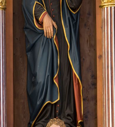 Zdjęcie nr 9: Przyścienną nastawę architektoniczną, trójosiową wykonano z drewna modrzewiowego. Jest to konstrukcja jednokondygnacyjna ze zwieńczeniem, w formie łuku triumfalnego, ustawiona na dwustrefowym cokole. Oś środkową wydzielają dwie pary kolumn o kapitelach kompozytowych i kanelowanych trzonach dźwigających wydłużone imposty. Kolumny wewnętrzne zostały połączone nad polem środkowym fryzem i gzymsem. Z kolei kolumny zewnętrze podtrzymują belkowanie zwieńczenia. Pole środkowe wypełnia nisza w formie stojącego prostokąta zamkniętego łukiem półkolistym z arkaturą z obrazem św. Andrzeja Apostoła. W osiach zewnętrznych usytuowano niższe flankowane parą kanelowanych kolumn z kapitelami kompozytowymi podtrzymujących imposty połączone nad polem fryzem i gzymsem. Nisze uzyskały kształt stojącego prostokąta zamkniętego łukiem półkolistym z arkaturą z figurami św. Wincentego a Paulo i św. Jana Kantego. Ponad niszami na belkowaniu usytuowano cokoły z figurami aniołów trzymających insygnia królewskie. Zwieńczenie uzyskało kształt leżącego prostokąta flankowanego dwiema parami złoconych kolumienek, dźwigających imposty i gzyms nad polem środkowym wyłamanym w trójkąt. Po bokach widoczne są spływy wolutowe. W polu znajduje się rama w formie kwadratu z wpisanym kołem z płaskorzeźbionym przedstawieniem Trójcy Świętej. Cokoły i imposty dekorowane zostały stylizowaną ornamentyką roślinną w postaci zwisów, kampanuli i girland. Struktura nastawy utrzymana jest w kolorze naturalnego drewna, natomiast ornamentyka, detale i profile zostały wyzłocone i wysrebrzone. Z kolei figury i płaskorzeźba w zwieńczeniu uzyskały naturalistyczną polichromię.