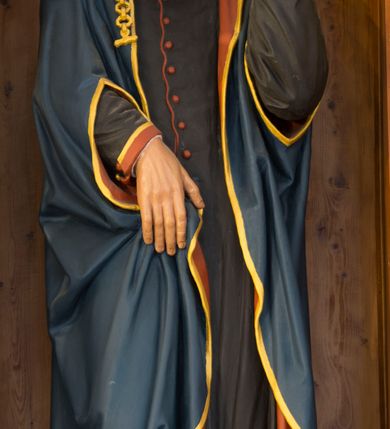 Zdjęcie nr 7: Przyścienną nastawę architektoniczną, trójosiową wykonano z drewna modrzewiowego. Jest to konstrukcja jednokondygnacyjna ze zwieńczeniem, w formie łuku triumfalnego, ustawiona na dwustrefowym cokole. Oś środkową wydzielają dwie pary kolumn o kapitelach kompozytowych i kanelowanych trzonach dźwigających wydłużone imposty. Kolumny wewnętrzne zostały połączone nad polem środkowym fryzem i gzymsem. Z kolei kolumny zewnętrze podtrzymują belkowanie zwieńczenia. Pole środkowe wypełnia nisza w formie stojącego prostokąta zamkniętego łukiem półkolistym z arkaturą z obrazem św. Andrzeja Apostoła. W osiach zewnętrznych usytuowano niższe flankowane parą kanelowanych kolumn z kapitelami kompozytowymi podtrzymujących imposty połączone nad polem fryzem i gzymsem. Nisze uzyskały kształt stojącego prostokąta zamkniętego łukiem półkolistym z arkaturą z figurami św. Wincentego a Paulo i św. Jana Kantego. Ponad niszami na belkowaniu usytuowano cokoły z figurami aniołów trzymających insygnia królewskie. Zwieńczenie uzyskało kształt leżącego prostokąta flankowanego dwiema parami złoconych kolumienek, dźwigających imposty i gzyms nad polem środkowym wyłamanym w trójkąt. Po bokach widoczne są spływy wolutowe. W polu znajduje się rama w formie kwadratu z wpisanym kołem z płaskorzeźbionym przedstawieniem Trójcy Świętej. Cokoły i imposty dekorowane zostały stylizowaną ornamentyką roślinną w postaci zwisów, kampanuli i girland. Struktura nastawy utrzymana jest w kolorze naturalnego drewna, natomiast ornamentyka, detale i profile zostały wyzłocone i wysrebrzone. Z kolei figury i płaskorzeźba w zwieńczeniu uzyskały naturalistyczną polichromię.