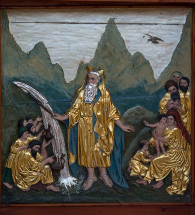 Zdjęcie nr 6: Przyścienną nastawę architektoniczną, trójosiową wykonano z drewna modrzewiowego. Jest to konstrukcja jednokondygnacyjna w formie łuku triumfalnego ze zwieńczeniem, ustawiona na dwustrefowym cokole. Stipes ołtarzowy uzyskał formę leżącego prostopadłościanu flankowanego po bokach spływami wolutowymi. W stipesie od przodu we wnęce pomiędzy dwoma pilastrami podtrzymującymi mensę umieszczono płaskorzeźbę z przedstawieniem Mojżesza wyprowadzającego wodę ze skały. Trzony pilastrów ozdobiono płaskorzeźbionym i złoconym ornamentem roślinnym. Na mensie na osi ustawiono
tabernakulum w formie leżącego prostopadłościanu o ściętych narożach, na niskim cokole, z profilowanym, niewielkim gzymsem, flankowanym na narożach pilastrami. Ścianka frontowa obwiedziona została rzędem złoconych okręgów. Na drzwiczkach umieszczono symbol Opatrzności Bożej od góry ujęte półkolistym łukiem. Oś środkową nastawy wydzielają dwie kolumny o kapitelach kompozytowych i kanelowanych trzonach dźwigających wydłużone imposty. Kolumny zostały połączone nad polem środkowym fryzem i gzymsem. Pole środkowe wypełnia nisza w formie stojącego prostokąta zamkniętego łukiem półkolistym z arkaturą z figurą św. Antoniego  Padwy oraz dwoma obrazami na zasuwach - "Niewiasty idące z Golgoty" oraz "Miłosierdzie Boże". W osiach zewnętrznych usytuowano niższe flankowane kanelowanymi kolumnami z kapitelami kompozytowymi, podtrzymującymi imposty połączone nad polem fryzem i gzymsem. Nisze uzyskały kształt stojącego prostokąta zamkniętego łukiem półkolistym z arkaturą z figurami apostołów św. Piotra i św. Pawła. Ponad niszami na belkowaniu usytuowano cokoły z figurami stojących aniołów ze złożonymi do modlitwy rękami. Zwieńczenie uzyskało kształt stojącego prostokąta flankowanego dwiema parami złoconych kolumienek, dźwigających imposty i gzyms nad polem środkowym wyłamanym w trójkąt. Po bokach widoczne są spływy wolutowe. Gzyms wieńczy krzyż i dwie złocone wazy. W polu zwieńczenia znajduje się rama w formie prostokąta z wpisanym owalem z obrazem św. Siostry Faustyny Kowalskiej. Ponad ramą widoczny jest chrystogram "IHS". Cokoły i imposty dekorowane zostały stylizowaną ornamentyką roślinną w postaci zwisów, kampanuli i girland. Struktura nastawy utrzymana jest w kolorze naturalnego drewna, natomiast ornamentyka, detale i profile zostały wyzłocone i wysrebrzone. Z kolei figury uzyskały naturalistyczną polichromię.