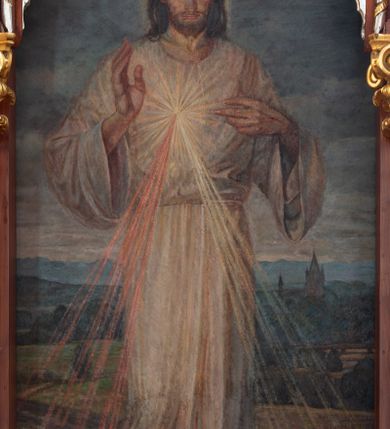 Zdjęcie nr 8: Przyścienną nastawę architektoniczną, trójosiową wykonano z drewna modrzewiowego. Jest to konstrukcja jednokondygnacyjna w formie łuku triumfalnego ze zwieńczeniem, ustawiona na dwustrefowym cokole. Stipes ołtarzowy uzyskał formę leżącego prostopadłościanu flankowanego po bokach spływami wolutowymi. W stipesie od przodu we wnęce pomiędzy dwoma pilastrami podtrzymującymi mensę umieszczono płaskorzeźbę z przedstawieniem Mojżesza wyprowadzającego wodę ze skały. Trzony pilastrów ozdobiono płaskorzeźbionym i złoconym ornamentem roślinnym. Na mensie na osi ustawiono
tabernakulum w formie leżącego prostopadłościanu o ściętych narożach, na niskim cokole, z profilowanym, niewielkim gzymsem, flankowanym na narożach pilastrami. Ścianka frontowa obwiedziona została rzędem złoconych okręgów. Na drzwiczkach umieszczono symbol Opatrzności Bożej od góry ujęte półkolistym łukiem. Oś środkową nastawy wydzielają dwie kolumny o kapitelach kompozytowych i kanelowanych trzonach dźwigających wydłużone imposty. Kolumny zostały połączone nad polem środkowym fryzem i gzymsem. Pole środkowe wypełnia nisza w formie stojącego prostokąta zamkniętego łukiem półkolistym z arkaturą z figurą św. Antoniego  Padwy oraz dwoma obrazami na zasuwach - &quot;Niewiasty idące z Golgoty&quot; oraz &quot;Miłosierdzie Boże&quot;. W osiach zewnętrznych usytuowano niższe flankowane kanelowanymi kolumnami z kapitelami kompozytowymi, podtrzymującymi imposty połączone nad polem fryzem i gzymsem. Nisze uzyskały kształt stojącego prostokąta zamkniętego łukiem półkolistym z arkaturą z figurami apostołów św. Piotra i św. Pawła. Ponad niszami na belkowaniu usytuowano cokoły z figurami stojących aniołów ze złożonymi do modlitwy rękami. Zwieńczenie uzyskało kształt stojącego prostokąta flankowanego dwiema parami złoconych kolumienek, dźwigających imposty i gzyms nad polem środkowym wyłamanym w trójkąt. Po bokach widoczne są spływy wolutowe. Gzyms wieńczy krzyż i dwie złocone wazy. W polu zwieńczenia znajduje się rama w formie prostokąta z wpisanym owalem z obrazem św. Siostry Faustyny Kowalskiej. Ponad ramą widoczny jest chrystogram &quot;IHS&quot;. Cokoły i imposty dekorowane zostały stylizowaną ornamentyką roślinną w postaci zwisów, kampanuli i girland. Struktura nastawy utrzymana jest w kolorze naturalnego drewna, natomiast ornamentyka, detale i profile zostały wyzłocone i wysrebrzone. Z kolei figury uzyskały naturalistyczną polichromię.