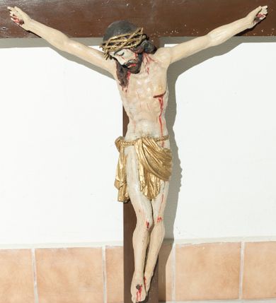 Zdjęcie nr 1: Rzeźba pełnoplastyczna, lekko ścięta z tyłu; z widocznym koluszkiem na plecach. Chrystus rozpięty na krzyżu w lekkim zwisie ciała, z szeroko rozłożonymi rękoma i nogami lekko ugiętymi w kolanach; stopy przybite jednym gwoździem, założone prawa na lewą. Ukazany jako martwy, z głową zwieszoną na prawy bark Twarz pociągła, z krótkim zarostem i długimi włosami spływającymi na plecy i na prawy bark. Ciało z podkreśloną budową anatomiczną i muskulaturą; w lewym boku rana. Na głowie korona cierniowa spleciona z trzech cienkich gałązek. Wokół bioder sznur podtrzymujący skąpe perizonium o formie pasa draperii. U góry, na pionowej belce krzyża umieszczony poziomo titulus o postrzępionych bokach, z literami INRI. Karnacja ciała w odcieniu naturalnym ze strużkami i kroplami krwi, włosy i zarost brązowe, titulus biały, korona cierniowa i perizonium pozłocone. 