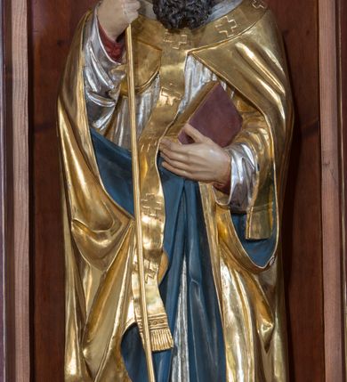 Zdjęcie nr 8: Przyścienną nastawę architektoniczną, trójosiową wykonano z drewna modrzewiowego. Jest to konstrukcja jednokondygnacyjna w formie łuku triumfalnego ze zwieńczeniem, ustawiona na dwustrefowym cokole. Stipes ołtarzowy uzyskał formę leżącego prostopadłościanu flankowanego po bokach spływami wolutowymi. W stipesie od przodu we wnęce pomiędzy dwoma pilastrami podtrzymującymi mensę umieszczono płaskorzeźbę z przedstawieniem odnoszącym się najprawdopodobniej do życia proroka Jonasza. Trzony pilastrów ozdobiono płaskorzeźbionym i złoconym ornamentem roślinnym. Oś środkową nastawy wydzielają dwie kolumny o kapitelach korynckich i kanelowanych trzonach dźwigających wydłużone imposty. Kolumny zostały połączone nad polem środkowym fryzem i gzymsem. Pole środkowe wypełnia nisza w formie stojącego prostokąta zamkniętego łukiem półkolistym z arkaturą z półkoliście zamkniętym obrazem Matki Boskiej Częstochowskiej. Na zasuwie umieszczono obraz św. Franciszka z Asyżu. W osiach zewnętrznych usytuowano niższe flankowane kanelowanymi kolumnami z kapitelami kompozytowymi, podtrzymującymi imposty połączone nad polem fryzem i gzymsem. Nisze uzyskały kształt stojącego prostokąta zamkniętego łukiem półkolistym z arkaturą z figurami św. Wojciecha i św. Stanisława. Ponad niszami na belkowaniu usytuowano cokoły z figurami stojących aniołów ze złożonymi do modlitwy rękami. Zwieńczenie uzyskało kształt stojącego prostokąta flankowanego dwiema parami złoconych kolumienek, dźwigających imposty i gzyms nad polem środkowym wyłamanym w trójkąt. Po bokach widoczne są spływy wolutowe. Gzyms wieńczy krzyż i dwie złocone wazy. W polu zwieńczenia znajduje się rama w formie prostokąta z wpisanym owalem z obrazem św. Bartłomieja Apostoła. Ponad ramą widoczny jest monogram maryjny. Cokoły i imposty dekorowane zostały stylizowaną ornamentyką roślinną w postaci zwisów, kampanuli i girland. Struktura nastawy utrzymana jest w kolorze naturalnego drewna, natomiast ornamentyka, detale i profile zostały wyzłocone i wysrebrzone. Z kolei figury uzyskały naturalistyczną polichromię.