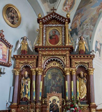 Zdjęcie nr 2: Przyścienną nastawę architektoniczną, trójosiową wykonano z drewna modrzewiowego. Jest to konstrukcja jednokondygnacyjna w formie łuku triumfalnego ze zwieńczeniem, ustawiona na dwustrefowym cokole. Stipes ołtarzowy uzyskał formę leżącego prostopadłościanu flankowanego po bokach spływami wolutowymi. W stipesie od przodu we wnęce pomiędzy dwoma pilastrami podtrzymującymi mensę umieszczono płaskorzeźbę z przedstawieniem odnoszącym się najprawdopodobniej do życia proroka Jonasza. Trzony pilastrów ozdobiono płaskorzeźbionym i złoconym ornamentem roślinnym. Oś środkową nastawy wydzielają dwie kolumny o kapitelach korynckich i kanelowanych trzonach dźwigających wydłużone imposty. Kolumny zostały połączone nad polem środkowym fryzem i gzymsem. Pole środkowe wypełnia nisza w formie stojącego prostokąta zamkniętego łukiem półkolistym z arkaturą z półkoliście zamkniętym obrazem Matki Boskiej Częstochowskiej. Na zasuwie umieszczono obraz św. Franciszka z Asyżu. W osiach zewnętrznych usytuowano niższe flankowane kanelowanymi kolumnami z kapitelami kompozytowymi, podtrzymującymi imposty połączone nad polem fryzem i gzymsem. Nisze uzyskały kształt stojącego prostokąta zamkniętego łukiem półkolistym z arkaturą z figurami św. Wojciecha i św. Stanisława. Ponad niszami na belkowaniu usytuowano cokoły z figurami stojących aniołów ze złożonymi do modlitwy rękami. Zwieńczenie uzyskało kształt stojącego prostokąta flankowanego dwiema parami złoconych kolumienek, dźwigających imposty i gzyms nad polem środkowym wyłamanym w trójkąt. Po bokach widoczne są spływy wolutowe. Gzyms wieńczy krzyż i dwie złocone wazy. W polu zwieńczenia znajduje się rama w formie prostokąta z wpisanym owalem z obrazem św. Bartłomieja Apostoła. Ponad ramą widoczny jest monogram maryjny. Cokoły i imposty dekorowane zostały stylizowaną ornamentyką roślinną w postaci zwisów, kampanuli i girland. Struktura nastawy utrzymana jest w kolorze naturalnego drewna, natomiast ornamentyka, detale i profile zostały wyzłocone i wysrebrzone. Z kolei figury uzyskały naturalistyczną polichromię.