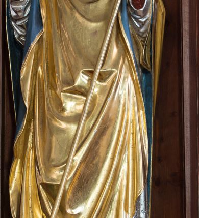 Zdjęcie nr 7: Przyścienną nastawę architektoniczną, trójosiową wykonano z drewna modrzewiowego. Jest to konstrukcja jednokondygnacyjna w formie łuku triumfalnego ze zwieńczeniem, ustawiona na dwustrefowym cokole. Stipes ołtarzowy uzyskał formę leżącego prostopadłościanu flankowanego po bokach spływami wolutowymi. W stipesie od przodu we wnęce pomiędzy dwoma pilastrami podtrzymującymi mensę umieszczono płaskorzeźbę z przedstawieniem odnoszącym się najprawdopodobniej do życia proroka Jonasza. Trzony pilastrów ozdobiono płaskorzeźbionym i złoconym ornamentem roślinnym. Oś środkową nastawy wydzielają dwie kolumny o kapitelach korynckich i kanelowanych trzonach dźwigających wydłużone imposty. Kolumny zostały połączone nad polem środkowym fryzem i gzymsem. Pole środkowe wypełnia nisza w formie stojącego prostokąta zamkniętego łukiem półkolistym z arkaturą z półkoliście zamkniętym obrazem Matki Boskiej Częstochowskiej. Na zasuwie umieszczono obraz św. Franciszka z Asyżu. W osiach zewnętrznych usytuowano niższe flankowane kanelowanymi kolumnami z kapitelami kompozytowymi, podtrzymującymi imposty połączone nad polem fryzem i gzymsem. Nisze uzyskały kształt stojącego prostokąta zamkniętego łukiem półkolistym z arkaturą z figurami św. Wojciecha i św. Stanisława. Ponad niszami na belkowaniu usytuowano cokoły z figurami stojących aniołów ze złożonymi do modlitwy rękami. Zwieńczenie uzyskało kształt stojącego prostokąta flankowanego dwiema parami złoconych kolumienek, dźwigających imposty i gzyms nad polem środkowym wyłamanym w trójkąt. Po bokach widoczne są spływy wolutowe. Gzyms wieńczy krzyż i dwie złocone wazy. W polu zwieńczenia znajduje się rama w formie prostokąta z wpisanym owalem z obrazem św. Bartłomieja Apostoła. Ponad ramą widoczny jest monogram maryjny. Cokoły i imposty dekorowane zostały stylizowaną ornamentyką roślinną w postaci zwisów, kampanuli i girland. Struktura nastawy utrzymana jest w kolorze naturalnego drewna, natomiast ornamentyka, detale i profile zostały wyzłocone i wysrebrzone. Z kolei figury uzyskały naturalistyczną polichromię.