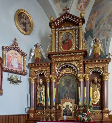 Zdjęcie nr 1: Przyścienną nastawę architektoniczną, trójosiową wykonano z drewna modrzewiowego. Jest to konstrukcja jednokondygnacyjna w formie łuku triumfalnego ze zwieńczeniem, ustawiona na dwustrefowym cokole. Stipes ołtarzowy uzyskał formę leżącego prostopadłościanu flankowanego po bokach spływami wolutowymi. W stipesie od przodu we wnęce pomiędzy dwoma pilastrami podtrzymującymi mensę umieszczono płaskorzeźbę z przedstawieniem odnoszącym się najprawdopodobniej do życia proroka Jonasza. Trzony pilastrów ozdobiono płaskorzeźbionym i złoconym ornamentem roślinnym. Oś środkową nastawy wydzielają dwie kolumny o kapitelach korynckich i kanelowanych trzonach dźwigających wydłużone imposty. Kolumny zostały połączone nad polem środkowym fryzem i gzymsem. Pole środkowe wypełnia nisza w formie stojącego prostokąta zamkniętego łukiem półkolistym z arkaturą z półkoliście zamkniętym obrazem Matki Boskiej Częstochowskiej. Na zasuwie umieszczono obraz św. Franciszka z Asyżu. W osiach zewnętrznych usytuowano niższe flankowane kanelowanymi kolumnami z kapitelami kompozytowymi, podtrzymującymi imposty połączone nad polem fryzem i gzymsem. Nisze uzyskały kształt stojącego prostokąta zamkniętego łukiem półkolistym z arkaturą z figurami św. Wojciecha i św. Stanisława. Ponad niszami na belkowaniu usytuowano cokoły z figurami stojących aniołów ze złożonymi do modlitwy rękami. Zwieńczenie uzyskało kształt stojącego prostokąta flankowanego dwiema parami złoconych kolumienek, dźwigających imposty i gzyms nad polem środkowym wyłamanym w trójkąt. Po bokach widoczne są spływy wolutowe. Gzyms wieńczy krzyż i dwie złocone wazy. W polu zwieńczenia znajduje się rama w formie prostokąta z wpisanym owalem z obrazem św. Bartłomieja Apostoła. Ponad ramą widoczny jest monogram maryjny. Cokoły i imposty dekorowane zostały stylizowaną ornamentyką roślinną w postaci zwisów, kampanuli i girland. Struktura nastawy utrzymana jest w kolorze naturalnego drewna, natomiast ornamentyka, detale i profile zostały wyzłocone i wysrebrzone. Z kolei figury uzyskały naturalistyczną polichromię.