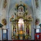 Zdjęcie nr 1: Ołtarz w kaplicy Matki Boskiej Szaflarskiej stanowi przykład przyściennej, architektonicznej, drewnianej nastawy trójosiowej ze zwieńczeniem. Stipes ołtarzowy z drewnianą mensą z kamiennym portatylem uzyskał kształt leżącego prostopadłościanu. Jego przód flankują hermy o trzonach dekorowanych cekinami. W polu zastosowano prostokątną płycinę ujętą kimationem. Na mensie ustawiono prostopadłościenne tabernakulum z wyodrębnionym cokołem i gzymsem koronującym wyłamanym na osi, podtrzymywanym przez dwa pilastry. Krawędzie tabernakulum zdobi imitacja boniowania. Drzwiczki ozdobiono stojącą, prostokątną płyciną, zwieńczoną trójkątnym przyczółkiem. W polu płyciny umieszczono stojący na obłokach płaskorzeźbiony i złocony kielich z hostią otoczoną promieniami. Jednokondygnacyjna nastawa wspiera się na prostokątnej predelli, przechodzącej pod osiami bocznymi w wolutowe konsole. Osie retabulum wydzielone zostały za pomocą skrajnych pilastrów oraz pary kolumn flankujących oś środkową. Podpory dźwigają pełne belkowanie wyłamane na ich osi, przerwane w partii pola środkowego oraz na osiach skrajnych przerwany półokrągły przyczółek. Wewnętrzna para kolumn dźwiga dodatkowo parę konsol podtrzymujących pełne belkowanie wyłamane na ich osi. Zwieńczenie uzyskało formę kwadratu zamkniętego szczytem z krzyżem, ujętego parą kolumienek na cokołach podtrzymujących skrajne woluty. Po zewnętrznych bokach zwieńczenia usytuowano postacie adorujących aniołów. W polu środkowym kondygnacji znalazła się nisza w formie stojącego prostokąta zamkniętego archiwoltą opadającą na belkowanie z konchą wydzieloną przez poziomy gzyms wsparty na dwóch pilastrach. W podniebiu konchy widoczna jest rzeźbiona i srebrzona gołębica Ducha Świętego. W niszy ustawiono figurę Matki Boskiej z Dzieciątkiem stojącą na wysokim czworobocznym postumencie. W osiach bocznych znalazły się nisze zamknięte konchą, u dołu podtrzymywane wspornikiem, z figurami św. Elżbiety Węgierskiej i św. Kazimierza Królewicza. W polu zwieńczenia umieszczono obraz w formie owalu ujęty ramą z przedstawieniem św. Maurycego. Ołtarz w całości pokryty został bogatą i zróżnicowaną dekoracją ornamentalną. Liśćmi akantu ozdobiono cokoły kolumn i wolut podwieszonych pod boczne osie. Kolumny w jednej czwartej wysokości obwiedzione zostały profilowaną listwą wypełnioną rautami. Ich dolne części ozdobiono uskrzydlonymi główkami aniołów z podwieszonymi festonami i girlandami. Z kolei w górnych partiach wykorzystano spiralne wici winnego grona. Dekoracyjnie artykułowano także pilastry, które w jednej czwartej przedzielono profilowanym gzymsem. Ich dolne części szczelnie wypełniono ornamentem okuciowym z rautem w środku, z kolei górne pokryto układającą się swobodnie i symetrycznie wstęgą z kaboszonami. Fryz belkowania wypełniony został wicią roślinną. Pola pomiędzy niszą a belkowaniem ozdobiono uskrzydlonymi główkami aniołów i podwieszonymi pod nimi girlandami. Ponadto uskrzydlone główki aniołów zdobią imposty podstawy zwieńczenia oraz klucz archiwolty ponad niszą główną. Kolumieńki zwieńczenia ozdobione zostały układającą się spiralnie wstęgą. Na dekoracje ornamentalną nastawy składają się również różne zdobienia profilów belkowania i zwieńczenia w postaci kostkowania, wolich oczu oraz pasów utworzonych z liści akantu.
