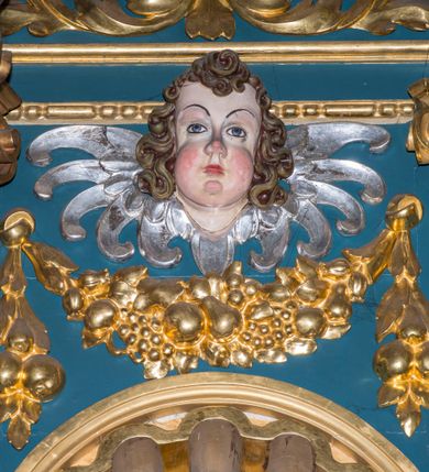 Zdjęcie nr 14: Ołtarz w kaplicy Matki Boskiej Szaflarskiej stanowi przykład przyściennej, architektonicznej, drewnianej nastawy trójosiowej ze zwieńczeniem. Stipes ołtarzowy z drewnianą mensą z kamiennym portatylem uzyskał kształt leżącego prostopadłościanu. Jego przód flankują hermy o trzonach dekorowanych cekinami. W polu zastosowano prostokątną płycinę ujętą kimationem. Na mensie ustawiono prostopadłościenne tabernakulum z wyodrębnionym cokołem i gzymsem koronującym wyłamanym na osi, podtrzymywanym przez dwa pilastry. Krawędzie tabernakulum zdobi imitacja boniowania. Drzwiczki ozdobiono stojącą, prostokątną płyciną, zwieńczoną trójkątnym przyczółkiem. W polu płyciny umieszczono stojący na obłokach płaskorzeźbiony i złocony kielich z hostią otoczoną promieniami. Jednokondygnacyjna nastawa wspiera się na prostokątnej predelli, przechodzącej pod osiami bocznymi w wolutowe konsole. Osie retabulum wydzielone zostały za pomocą skrajnych pilastrów oraz pary kolumn flankujących oś środkową. Podpory dźwigają pełne belkowanie wyłamane na ich osi, przerwane w partii pola środkowego oraz na osiach skrajnych przerwany półokrągły przyczółek. Wewnętrzna para kolumn dźwiga dodatkowo parę konsol podtrzymujących pełne belkowanie wyłamane na ich osi. Zwieńczenie uzyskało formę kwadratu zamkniętego szczytem z krzyżem, ujętego parą kolumienek na cokołach podtrzymujących skrajne woluty. Po zewnętrznych bokach zwieńczenia usytuowano postacie adorujących aniołów. W polu środkowym kondygnacji znalazła się nisza w formie stojącego prostokąta zamkniętego archiwoltą opadającą na belkowanie z konchą wydzieloną przez poziomy gzyms wsparty na dwóch pilastrach. W podniebiu konchy widoczna jest rzeźbiona i srebrzona gołębica Ducha Świętego. W niszy ustawiono figurę Matki Boskiej z Dzieciątkiem stojącą na wysokim czworobocznym postumencie. W osiach bocznych znalazły się nisze zamknięte konchą, u dołu podtrzymywane wspornikiem, z figurami św. Elżbiety Węgierskiej i św. Kazimierza Królewicza. W polu zwieńczenia umieszczono obraz w formie owalu ujęty ramą z przedstawieniem św. Maurycego. Ołtarz w całości pokryty został bogatą i zróżnicowaną dekoracją ornamentalną. Liśćmi akantu ozdobiono cokoły kolumn i wolut podwieszonych pod boczne osie. Kolumny w jednej czwartej wysokości obwiedzione zostały profilowaną listwą wypełnioną rautami. Ich dolne części ozdobiono uskrzydlonymi główkami aniołów z podwieszonymi festonami i girlandami. Z kolei w górnych partiach wykorzystano spiralne wici winnego grona. Dekoracyjnie artykułowano także pilastry, które w jednej czwartej przedzielono profilowanym gzymsem. Ich dolne części szczelnie wypełniono ornamentem okuciowym z rautem w środku, z kolei górne pokryto układającą się swobodnie i symetrycznie wstęgą z kaboszonami. Fryz belkowania wypełniony został wicią roślinną. Pola pomiędzy niszą a belkowaniem ozdobiono uskrzydlonymi główkami aniołów i podwieszonymi pod nimi girlandami. Ponadto uskrzydlone główki aniołów zdobią imposty podstawy zwieńczenia oraz klucz archiwolty ponad niszą główną. Kolumieńki zwieńczenia ozdobione zostały układającą się spiralnie wstęgą. Na dekoracje ornamentalną nastawy składają się również różne zdobienia profilów belkowania i zwieńczenia w postaci kostkowania, wolich oczu oraz pasów utworzonych z liści akantu.
