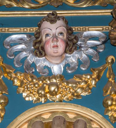 Zdjęcie nr 15: Ołtarz w kaplicy Matki Boskiej Szaflarskiej stanowi przykład przyściennej, architektonicznej, drewnianej nastawy trójosiowej ze zwieńczeniem. Stipes ołtarzowy z drewnianą mensą z kamiennym portatylem uzyskał kształt leżącego prostopadłościanu. Jego przód flankują hermy o trzonach dekorowanych cekinami. W polu zastosowano prostokątną płycinę ujętą kimationem. Na mensie ustawiono prostopadłościenne tabernakulum z wyodrębnionym cokołem i gzymsem koronującym wyłamanym na osi, podtrzymywanym przez dwa pilastry. Krawędzie tabernakulum zdobi imitacja boniowania. Drzwiczki ozdobiono stojącą, prostokątną płyciną, zwieńczoną trójkątnym przyczółkiem. W polu płyciny umieszczono stojący na obłokach płaskorzeźbiony i złocony kielich z hostią otoczoną promieniami. Jednokondygnacyjna nastawa wspiera się na prostokątnej predelli, przechodzącej pod osiami bocznymi w wolutowe konsole. Osie retabulum wydzielone zostały za pomocą skrajnych pilastrów oraz pary kolumn flankujących oś środkową. Podpory dźwigają pełne belkowanie wyłamane na ich osi, przerwane w partii pola środkowego oraz na osiach skrajnych przerwany półokrągły przyczółek. Wewnętrzna para kolumn dźwiga dodatkowo parę konsol podtrzymujących pełne belkowanie wyłamane na ich osi. Zwieńczenie uzyskało formę kwadratu zamkniętego szczytem z krzyżem, ujętego parą kolumienek na cokołach podtrzymujących skrajne woluty. Po zewnętrznych bokach zwieńczenia usytuowano postacie adorujących aniołów. W polu środkowym kondygnacji znalazła się nisza w formie stojącego prostokąta zamkniętego archiwoltą opadającą na belkowanie z konchą wydzieloną przez poziomy gzyms wsparty na dwóch pilastrach. W podniebiu konchy widoczna jest rzeźbiona i srebrzona gołębica Ducha Świętego. W niszy ustawiono figurę Matki Boskiej z Dzieciątkiem stojącą na wysokim czworobocznym postumencie. W osiach bocznych znalazły się nisze zamknięte konchą, u dołu podtrzymywane wspornikiem, z figurami św. Elżbiety Węgierskiej i św. Kazimierza Królewicza. W polu zwieńczenia umieszczono obraz w formie owalu ujęty ramą z przedstawieniem św. Maurycego. Ołtarz w całości pokryty został bogatą i zróżnicowaną dekoracją ornamentalną. Liśćmi akantu ozdobiono cokoły kolumn i wolut podwieszonych pod boczne osie. Kolumny w jednej czwartej wysokości obwiedzione zostały profilowaną listwą wypełnioną rautami. Ich dolne części ozdobiono uskrzydlonymi główkami aniołów z podwieszonymi festonami i girlandami. Z kolei w górnych partiach wykorzystano spiralne wici winnego grona. Dekoracyjnie artykułowano także pilastry, które w jednej czwartej przedzielono profilowanym gzymsem. Ich dolne części szczelnie wypełniono ornamentem okuciowym z rautem w środku, z kolei górne pokryto układającą się swobodnie i symetrycznie wstęgą z kaboszonami. Fryz belkowania wypełniony został wicią roślinną. Pola pomiędzy niszą a belkowaniem ozdobiono uskrzydlonymi główkami aniołów i podwieszonymi pod nimi girlandami. Ponadto uskrzydlone główki aniołów zdobią imposty podstawy zwieńczenia oraz klucz archiwolty ponad niszą główną. Kolumieńki zwieńczenia ozdobione zostały układającą się spiralnie wstęgą. Na dekoracje ornamentalną nastawy składają się również różne zdobienia profilów belkowania i zwieńczenia w postaci kostkowania, wolich oczu oraz pasów utworzonych z liści akantu.
