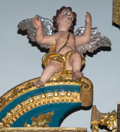 Zdjęcie nr 17: Ołtarz w kaplicy Matki Boskiej Szaflarskiej stanowi przykład przyściennej, architektonicznej, drewnianej nastawy trójosiowej ze zwieńczeniem. Stipes ołtarzowy z drewnianą mensą z kamiennym portatylem uzyskał kształt leżącego prostopadłościanu. Jego przód flankują hermy o trzonach dekorowanych cekinami. W polu zastosowano prostokątną płycinę ujętą kimationem. Na mensie ustawiono prostopadłościenne tabernakulum z wyodrębnionym cokołem i gzymsem koronującym wyłamanym na osi, podtrzymywanym przez dwa pilastry. Krawędzie tabernakulum zdobi imitacja boniowania. Drzwiczki ozdobiono stojącą, prostokątną płyciną, zwieńczoną trójkątnym przyczółkiem. W polu płyciny umieszczono stojący na obłokach płaskorzeźbiony i złocony kielich z hostią otoczoną promieniami. Jednokondygnacyjna nastawa wspiera się na prostokątnej predelli, przechodzącej pod osiami bocznymi w wolutowe konsole. Osie retabulum wydzielone zostały za pomocą skrajnych pilastrów oraz pary kolumn flankujących oś środkową. Podpory dźwigają pełne belkowanie wyłamane na ich osi, przerwane w partii pola środkowego oraz na osiach skrajnych przerwany półokrągły przyczółek. Wewnętrzna para kolumn dźwiga dodatkowo parę konsol podtrzymujących pełne belkowanie wyłamane na ich osi. Zwieńczenie uzyskało formę kwadratu zamkniętego szczytem z krzyżem, ujętego parą kolumienek na cokołach podtrzymujących skrajne woluty. Po zewnętrznych bokach zwieńczenia usytuowano postacie adorujących aniołów. W polu środkowym kondygnacji znalazła się nisza w formie stojącego prostokąta zamkniętego archiwoltą opadającą na belkowanie z konchą wydzieloną przez poziomy gzyms wsparty na dwóch pilastrach. W podniebiu konchy widoczna jest rzeźbiona i srebrzona gołębica Ducha Świętego. W niszy ustawiono figurę Matki Boskiej z Dzieciątkiem stojącą na wysokim czworobocznym postumencie. W osiach bocznych znalazły się nisze zamknięte konchą, u dołu podtrzymywane wspornikiem, z figurami św. Elżbiety Węgierskiej i św. Kazimierza Królewicza. W polu zwieńczenia umieszczono obraz w formie owalu ujęty ramą z przedstawieniem św. Maurycego. Ołtarz w całości pokryty został bogatą i zróżnicowaną dekoracją ornamentalną. Liśćmi akantu ozdobiono cokoły kolumn i wolut podwieszonych pod boczne osie. Kolumny w jednej czwartej wysokości obwiedzione zostały profilowaną listwą wypełnioną rautami. Ich dolne części ozdobiono uskrzydlonymi główkami aniołów z podwieszonymi festonami i girlandami. Z kolei w górnych partiach wykorzystano spiralne wici winnego grona. Dekoracyjnie artykułowano także pilastry, które w jednej czwartej przedzielono profilowanym gzymsem. Ich dolne części szczelnie wypełniono ornamentem okuciowym z rautem w środku, z kolei górne pokryto układającą się swobodnie i symetrycznie wstęgą z kaboszonami. Fryz belkowania wypełniony został wicią roślinną. Pola pomiędzy niszą a belkowaniem ozdobiono uskrzydlonymi główkami aniołów i podwieszonymi pod nimi girlandami. Ponadto uskrzydlone główki aniołów zdobią imposty podstawy zwieńczenia oraz klucz archiwolty ponad niszą główną. Kolumieńki zwieńczenia ozdobione zostały układającą się spiralnie wstęgą. Na dekoracje ornamentalną nastawy składają się również różne zdobienia profilów belkowania i zwieńczenia w postaci kostkowania, wolich oczu oraz pasów utworzonych z liści akantu.
