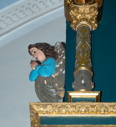 Zdjęcie nr 25: Ołtarz w kaplicy Matki Boskiej Szaflarskiej stanowi przykład przyściennej, architektonicznej, drewnianej nastawy trójosiowej ze zwieńczeniem. Stipes ołtarzowy z drewnianą mensą z kamiennym portatylem uzyskał kształt leżącego prostopadłościanu. Jego przód flankują hermy o trzonach dekorowanych cekinami. W polu zastosowano prostokątną płycinę ujętą kimationem. Na mensie ustawiono prostopadłościenne tabernakulum z wyodrębnionym cokołem i gzymsem koronującym wyłamanym na osi, podtrzymywanym przez dwa pilastry. Krawędzie tabernakulum zdobi imitacja boniowania. Drzwiczki ozdobiono stojącą, prostokątną płyciną, zwieńczoną trójkątnym przyczółkiem. W polu płyciny umieszczono stojący na obłokach płaskorzeźbiony i złocony kielich z hostią otoczoną promieniami. Jednokondygnacyjna nastawa wspiera się na prostokątnej predelli, przechodzącej pod osiami bocznymi w wolutowe konsole. Osie retabulum wydzielone zostały za pomocą skrajnych pilastrów oraz pary kolumn flankujących oś środkową. Podpory dźwigają pełne belkowanie wyłamane na ich osi, przerwane w partii pola środkowego oraz na osiach skrajnych przerwany półokrągły przyczółek. Wewnętrzna para kolumn dźwiga dodatkowo parę konsol podtrzymujących pełne belkowanie wyłamane na ich osi. Zwieńczenie uzyskało formę kwadratu zamkniętego szczytem z krzyżem, ujętego parą kolumienek na cokołach podtrzymujących skrajne woluty. Po zewnętrznych bokach zwieńczenia usytuowano postacie adorujących aniołów. W polu środkowym kondygnacji znalazła się nisza w formie stojącego prostokąta zamkniętego archiwoltą opadającą na belkowanie z konchą wydzieloną przez poziomy gzyms wsparty na dwóch pilastrach. W podniebiu konchy widoczna jest rzeźbiona i srebrzona gołębica Ducha Świętego. W niszy ustawiono figurę Matki Boskiej z Dzieciątkiem stojącą na wysokim czworobocznym postumencie. W osiach bocznych znalazły się nisze zamknięte konchą, u dołu podtrzymywane wspornikiem, z figurami św. Elżbiety Węgierskiej i św. Kazimierza Królewicza. W polu zwieńczenia umieszczono obraz w formie owalu ujęty ramą z przedstawieniem św. Maurycego. Ołtarz w całości pokryty został bogatą i zróżnicowaną dekoracją ornamentalną. Liśćmi akantu ozdobiono cokoły kolumn i wolut podwieszonych pod boczne osie. Kolumny w jednej czwartej wysokości obwiedzione zostały profilowaną listwą wypełnioną rautami. Ich dolne części ozdobiono uskrzydlonymi główkami aniołów z podwieszonymi festonami i girlandami. Z kolei w górnych partiach wykorzystano spiralne wici winnego grona. Dekoracyjnie artykułowano także pilastry, które w jednej czwartej przedzielono profilowanym gzymsem. Ich dolne części szczelnie wypełniono ornamentem okuciowym z rautem w środku, z kolei górne pokryto układającą się swobodnie i symetrycznie wstęgą z kaboszonami. Fryz belkowania wypełniony został wicią roślinną. Pola pomiędzy niszą a belkowaniem ozdobiono uskrzydlonymi główkami aniołów i podwieszonymi pod nimi girlandami. Ponadto uskrzydlone główki aniołów zdobią imposty podstawy zwieńczenia oraz klucz archiwolty ponad niszą główną. Kolumieńki zwieńczenia ozdobione zostały układającą się spiralnie wstęgą. Na dekoracje ornamentalną nastawy składają się również różne zdobienia profilów belkowania i zwieńczenia w postaci kostkowania, wolich oczu oraz pasów utworzonych z liści akantu.
