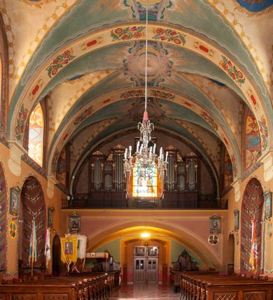 Zdjęcie nr 16: Kościół jest położony na wzgórzu w pobliżu centrum, przy ul. Brata Alojzego Kosiby. Od zachodu przed kościołem znajduje się dziedziniec i dawny cmentarz obwiedzione murem z bramkami i stacjami Męki Pańskiej. Z cmentarza wejście prowadzi do kościoła, a przez furtę na teren przyklasztorny i dalej do ogrodu klasztornego. Kościół wzniesiony jest z cegły, otynkowany. Świątynia jest orientowana, jednonawowa, z węższym prezbiterium, z kaplicą od północy i kruchtą od zachodu. Przy kościele od południa znajdują się zakrystia i zabudowania klasztorne. Prezbiterium na rzucie prostokąta, zamknięte od wschodu prostą ścianą, trójprzęsłowe, przekryte sklepieniem kolebkowym z przecinającymi się lunetami. W każdym przęśle ściany północnej wysoko umieszczone półkoliście zamknięte okna. Otworom okiennym odpowiadają tej samej wielkości nisze umieszczone w ścianie południowej. Wejście do klasztornego korytarza i zakrystii umieszczone jest w przęśle środkowym. Odpowiada mu otwór komunikacyjny po stronie przeciwnej. W przęśle zachodnim zlokalizowano drugie wejście do południowego korytarza klasztornego. Przestrzeń miedzy prezbiterium a korpusem zawężona arkadą tęczową, zamkniętą półkoliście. Korpus jednonawowy, szerszy z wnękami na ołtarze, czteroprzęsłowy, przekryty sklepieniem kolebkowym na gurtach z lunetami. Wnęka w trzecim przęśle od wschodu zamieniona na otwór do kaplicy północnej. Połowę przęsła zachodniego zajmuje empora muzyczna oparta na nisko schodzącym sklepieniu kolebkowym. Przy emporze, w ścianach wzdłużnych nawy, znacznie mniejsze, półkoliście zamknięte wnęki na konfesjonały. W lunetach, po obu stronach półkoliście zamknięte okna. Okna w przęśle zachodnim zastępują tej samej wielkości nisze. Główne wejście do kościoła w osi ściany zachodniej, zamknięte łukiem odcinkowym. W osi nad chórem muzycznym, półkoliście zamknięte okno, większe od pozostałych. Wejście do kościoła objęte prostokątnym portalem z piaskowca. Kaplica północna wzniesiona na planie kwadratu, przekryta sklepieniem współczesnym, zbliżonym w formie do klasztornego, zwieńczona latarnią. Okna, umieszczone w ścianie wschodniej i zachodniej, o tym samym wykroju utworzonym z wąskiego prostokąta przechodzącego górą w formę wachlarza lub wycinka koła. Zewnętrzne elewacje artykułuje podział osiowy i dekoracja lizenowo-ramowa, złożona z wydatnych elementów wertykalnych i horyzontalnych. Jednoosiową fasadę nad kruchtą ozdabia poniżej okna profilowany gzyms. Całość zamknięta wysoką, trójkątną ścianą szczytową, z trzema półkoliście zamkniętymi niszami. W nich polichromowane płaskorzeźby o kształcie stojącego prostokąta zamkniętego łukiem pełnym przedstawiające: stygmatyzację św. Franciszka, św. Piotra z Alkantary, św. Antoniego Padewskiego. Szczyt zwieńczony metalowym krzyżem osadzonym na niskim cokole. Kruchta przy fasadzie  z dwoma wejściami. Wejście zachodnie obejmuje półkoliście zamknięty portal z piaskowca, z dekoracją płycinową na węgarach, z kapitelami i skromnie profilowaną archiwoltą spiętą kluczem. Węższe wejście od północy z prostym, półkoliście zamkniętym portalem z piaskowca. Budowlę zamkniętą profilowanym gzymsem wieńczy trójkątny naczółek, przechodzący po bokach w balustradę z dekoracją płycinową. Na narożnych słupkach balustrady obeliskowe sterczyny. W półkoliście zamkniętej wnęce, umieszczonej pośrodku naczółka, wizerunek Matki Boskiej Nieustającej Pomocy. Wschodnia ściana prezbiterium, w dolnej partii zupełnie płaska, w górnej z triadą prostokątnych wnęk. Część szczytową oddziela od dolnej profilowany gzyms kryty dachówką. W osi trójkątnego szczytu wschodniego prostokątna wnęka z płaskorzeźbioną i polichromowaną sceną przedstawiającą św. Porcjunkulę w towarzystwie Chrystusa oraz św. Franciszka. Bryłę świątyni zamykają wysokie dachy dwuspadowe. Pośrodku dachu prezbiterium wieloboczna wieżyczka na sygnaturkę z ażurową latarnią. Bryłę kaplicy przekrywa dach czterospadowy. Ośmioboczną formę jej latarni zamyka dach wielospadowy zwieńczony metalowym krzyżem.