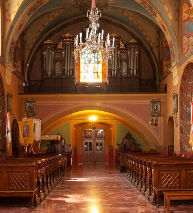 Zdjęcie nr 17: Kościół jest położony na wzgórzu w pobliżu centrum, przy ul. Brata Alojzego Kosiby. Od zachodu przed kościołem znajduje się dziedziniec i dawny cmentarz obwiedzione murem z bramkami i stacjami Męki Pańskiej. Z cmentarza wejście prowadzi do kościoła, a przez furtę na teren przyklasztorny i dalej do ogrodu klasztornego. Kościół wzniesiony jest z cegły, otynkowany. Świątynia jest orientowana, jednonawowa, z węższym prezbiterium, z kaplicą od północy i kruchtą od zachodu. Przy kościele od południa znajdują się zakrystia i zabudowania klasztorne. Prezbiterium na rzucie prostokąta, zamknięte od wschodu prostą ścianą, trójprzęsłowe, przekryte sklepieniem kolebkowym z przecinającymi się lunetami. W każdym przęśle ściany północnej wysoko umieszczone półkoliście zamknięte okna. Otworom okiennym odpowiadają tej samej wielkości nisze umieszczone w ścianie południowej. Wejście do klasztornego korytarza i zakrystii umieszczone jest w przęśle środkowym. Odpowiada mu otwór komunikacyjny po stronie przeciwnej. W przęśle zachodnim zlokalizowano drugie wejście do południowego korytarza klasztornego. Przestrzeń miedzy prezbiterium a korpusem zawężona arkadą tęczową, zamkniętą półkoliście. Korpus jednonawowy, szerszy z wnękami na ołtarze, czteroprzęsłowy, przekryty sklepieniem kolebkowym na gurtach z lunetami. Wnęka w trzecim przęśle od wschodu zamieniona na otwór do kaplicy północnej. Połowę przęsła zachodniego zajmuje empora muzyczna oparta na nisko schodzącym sklepieniu kolebkowym. Przy emporze, w ścianach wzdłużnych nawy, znacznie mniejsze, półkoliście zamknięte wnęki na konfesjonały. W lunetach, po obu stronach półkoliście zamknięte okna. Okna w przęśle zachodnim zastępują tej samej wielkości nisze. Główne wejście do kościoła w osi ściany zachodniej, zamknięte łukiem odcinkowym. W osi nad chórem muzycznym, półkoliście zamknięte okno, większe od pozostałych. Wejście do kościoła objęte prostokątnym portalem z piaskowca. Kaplica północna wzniesiona na planie kwadratu, przekryta sklepieniem współczesnym, zbliżonym w formie do klasztornego, zwieńczona latarnią. Okna, umieszczone w ścianie wschodniej i zachodniej, o tym samym wykroju utworzonym z wąskiego prostokąta przechodzącego górą w formę wachlarza lub wycinka koła. Zewnętrzne elewacje artykułuje podział osiowy i dekoracja lizenowo-ramowa, złożona z wydatnych elementów wertykalnych i horyzontalnych. Jednoosiową fasadę nad kruchtą ozdabia poniżej okna profilowany gzyms. Całość zamknięta wysoką, trójkątną ścianą szczytową, z trzema półkoliście zamkniętymi niszami. W nich polichromowane płaskorzeźby o kształcie stojącego prostokąta zamkniętego łukiem pełnym przedstawiające: stygmatyzację św. Franciszka, św. Piotra z Alkantary, św. Antoniego Padewskiego. Szczyt zwieńczony metalowym krzyżem osadzonym na niskim cokole. Kruchta przy fasadzie  z dwoma wejściami. Wejście zachodnie obejmuje półkoliście zamknięty portal z piaskowca, z dekoracją płycinową na węgarach, z kapitelami i skromnie profilowaną archiwoltą spiętą kluczem. Węższe wejście od północy z prostym, półkoliście zamkniętym portalem z piaskowca. Budowlę zamkniętą profilowanym gzymsem wieńczy trójkątny naczółek, przechodzący po bokach w balustradę z dekoracją płycinową. Na narożnych słupkach balustrady obeliskowe sterczyny. W półkoliście zamkniętej wnęce, umieszczonej pośrodku naczółka, wizerunek Matki Boskiej Nieustającej Pomocy. Wschodnia ściana prezbiterium, w dolnej partii zupełnie płaska, w górnej z triadą prostokątnych wnęk. Część szczytową oddziela od dolnej profilowany gzyms kryty dachówką. W osi trójkątnego szczytu wschodniego prostokątna wnęka z płaskorzeźbioną i polichromowaną sceną przedstawiającą św. Porcjunkulę w towarzystwie Chrystusa oraz św. Franciszka. Bryłę świątyni zamykają wysokie dachy dwuspadowe. Pośrodku dachu prezbiterium wieloboczna wieżyczka na sygnaturkę z ażurową latarnią. Bryłę kaplicy przekrywa dach czterospadowy. Ośmioboczną formę jej latarni zamyka dach wielospadowy zwieńczony metalowym krzyżem.