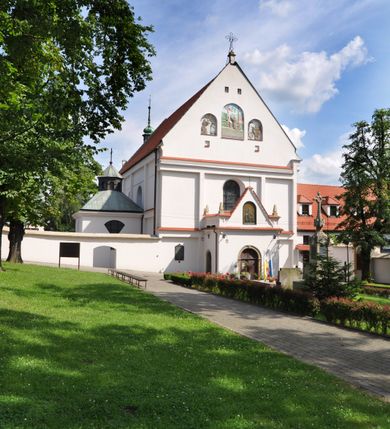 Zdjęcie nr 3: Kościół jest położony na wzgórzu w pobliżu centrum, przy ul. Brata Alojzego Kosiby. Od zachodu przed kościołem znajduje się dziedziniec i dawny cmentarz obwiedzione murem z bramkami i stacjami Męki Pańskiej. Z cmentarza wejście prowadzi do kościoła, a przez furtę na teren przyklasztorny i dalej do ogrodu klasztornego. Kościół wzniesiony jest z cegły, otynkowany. Świątynia jest orientowana, jednonawowa, z węższym prezbiterium, z kaplicą od północy i kruchtą od zachodu. Przy kościele od południa znajdują się zakrystia i zabudowania klasztorne. Prezbiterium na rzucie prostokąta, zamknięte od wschodu prostą ścianą, trójprzęsłowe, przekryte sklepieniem kolebkowym z przecinającymi się lunetami. W każdym przęśle ściany północnej wysoko umieszczone półkoliście zamknięte okna. Otworom okiennym odpowiadają tej samej wielkości nisze umieszczone w ścianie południowej. Wejście do klasztornego korytarza i zakrystii umieszczone jest w przęśle środkowym. Odpowiada mu otwór komunikacyjny po stronie przeciwnej. W przęśle zachodnim zlokalizowano drugie wejście do południowego korytarza klasztornego. Przestrzeń miedzy prezbiterium a korpusem zawężona arkadą tęczową, zamkniętą półkoliście. Korpus jednonawowy, szerszy z wnękami na ołtarze, czteroprzęsłowy, przekryty sklepieniem kolebkowym na gurtach z lunetami. Wnęka w trzecim przęśle od wschodu zamieniona na otwór do kaplicy północnej. Połowę przęsła zachodniego zajmuje empora muzyczna oparta na nisko schodzącym sklepieniu kolebkowym. Przy emporze, w ścianach wzdłużnych nawy, znacznie mniejsze, półkoliście zamknięte wnęki na konfesjonały. W lunetach, po obu stronach półkoliście zamknięte okna. Okna w przęśle zachodnim zastępują tej samej wielkości nisze. Główne wejście do kościoła w osi ściany zachodniej, zamknięte łukiem odcinkowym. W osi nad chórem muzycznym, półkoliście zamknięte okno, większe od pozostałych. Wejście do kościoła objęte prostokątnym portalem z piaskowca. Kaplica północna wzniesiona na planie kwadratu, przekryta sklepieniem współczesnym, zbliżonym w formie do klasztornego, zwieńczona latarnią. Okna, umieszczone w ścianie wschodniej i zachodniej, o tym samym wykroju utworzonym z wąskiego prostokąta przechodzącego górą w formę wachlarza lub wycinka koła. Zewnętrzne elewacje artykułuje podział osiowy i dekoracja lizenowo-ramowa, złożona z wydatnych elementów wertykalnych i horyzontalnych. Jednoosiową fasadę nad kruchtą ozdabia poniżej okna profilowany gzyms. Całość zamknięta wysoką, trójkątną ścianą szczytową, z trzema półkoliście zamkniętymi niszami. W nich polichromowane płaskorzeźby o kształcie stojącego prostokąta zamkniętego łukiem pełnym przedstawiające: stygmatyzację św. Franciszka, św. Piotra z Alkantary, św. Antoniego Padewskiego. Szczyt zwieńczony metalowym krzyżem osadzonym na niskim cokole. Kruchta przy fasadzie  z dwoma wejściami. Wejście zachodnie obejmuje półkoliście zamknięty portal z piaskowca, z dekoracją płycinową na węgarach, z kapitelami i skromnie profilowaną archiwoltą spiętą kluczem. Węższe wejście od północy z prostym, półkoliście zamkniętym portalem z piaskowca. Budowlę zamkniętą profilowanym gzymsem wieńczy trójkątny naczółek, przechodzący po bokach w balustradę z dekoracją płycinową. Na narożnych słupkach balustrady obeliskowe sterczyny. W półkoliście zamkniętej wnęce, umieszczonej pośrodku naczółka, wizerunek Matki Boskiej Nieustającej Pomocy. Wschodnia ściana prezbiterium, w dolnej partii zupełnie płaska, w górnej z triadą prostokątnych wnęk. Część szczytową oddziela od dolnej profilowany gzyms kryty dachówką. W osi trójkątnego szczytu wschodniego prostokątna wnęka z płaskorzeźbioną i polichromowaną sceną przedstawiającą św. Porcjunkulę w towarzystwie Chrystusa oraz św. Franciszka. Bryłę świątyni zamykają wysokie dachy dwuspadowe. Pośrodku dachu prezbiterium wieloboczna wieżyczka na sygnaturkę z ażurową latarnią. Bryłę kaplicy przekrywa dach czterospadowy. Ośmioboczną formę jej latarni zamyka dach wielospadowy zwieńczony metalowym krzyżem.