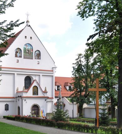 Zdjęcie nr 7: Kościół jest położony na wzgórzu w pobliżu centrum, przy ul. Brata Alojzego Kosiby. Od zachodu przed kościołem znajduje się dziedziniec i dawny cmentarz obwiedzione murem z bramkami i stacjami Męki Pańskiej. Z cmentarza wejście prowadzi do kościoła, a przez furtę na teren przyklasztorny i dalej do ogrodu klasztornego. Kościół wzniesiony jest z cegły, otynkowany. Świątynia jest orientowana, jednonawowa, z węższym prezbiterium, z kaplicą od północy i kruchtą od zachodu. Przy kościele od południa znajdują się zakrystia i zabudowania klasztorne. Prezbiterium na rzucie prostokąta, zamknięte od wschodu prostą ścianą, trójprzęsłowe, przekryte sklepieniem kolebkowym z przecinającymi się lunetami. W każdym przęśle ściany północnej wysoko umieszczone półkoliście zamknięte okna. Otworom okiennym odpowiadają tej samej wielkości nisze umieszczone w ścianie południowej. Wejście do klasztornego korytarza i zakrystii umieszczone jest w przęśle środkowym. Odpowiada mu otwór komunikacyjny po stronie przeciwnej. W przęśle zachodnim zlokalizowano drugie wejście do południowego korytarza klasztornego. Przestrzeń miedzy prezbiterium a korpusem zawężona arkadą tęczową, zamkniętą półkoliście. Korpus jednonawowy, szerszy z wnękami na ołtarze, czteroprzęsłowy, przekryty sklepieniem kolebkowym na gurtach z lunetami. Wnęka w trzecim przęśle od wschodu zamieniona na otwór do kaplicy północnej. Połowę przęsła zachodniego zajmuje empora muzyczna oparta na nisko schodzącym sklepieniu kolebkowym. Przy emporze, w ścianach wzdłużnych nawy, znacznie mniejsze, półkoliście zamknięte wnęki na konfesjonały. W lunetach, po obu stronach półkoliście zamknięte okna. Okna w przęśle zachodnim zastępują tej samej wielkości nisze. Główne wejście do kościoła w osi ściany zachodniej, zamknięte łukiem odcinkowym. W osi nad chórem muzycznym, półkoliście zamknięte okno, większe od pozostałych. Wejście do kościoła objęte prostokątnym portalem z piaskowca. Kaplica północna wzniesiona na planie kwadratu, przekryta sklepieniem współczesnym, zbliżonym w formie do klasztornego, zwieńczona latarnią. Okna, umieszczone w ścianie wschodniej i zachodniej, o tym samym wykroju utworzonym z wąskiego prostokąta przechodzącego górą w formę wachlarza lub wycinka koła. Zewnętrzne elewacje artykułuje podział osiowy i dekoracja lizenowo-ramowa, złożona z wydatnych elementów wertykalnych i horyzontalnych. Jednoosiową fasadę nad kruchtą ozdabia poniżej okna profilowany gzyms. Całość zamknięta wysoką, trójkątną ścianą szczytową, z trzema półkoliście zamkniętymi niszami. W nich polichromowane płaskorzeźby o kształcie stojącego prostokąta zamkniętego łukiem pełnym przedstawiające: stygmatyzację św. Franciszka, św. Piotra z Alkantary, św. Antoniego Padewskiego. Szczyt zwieńczony metalowym krzyżem osadzonym na niskim cokole. Kruchta przy fasadzie  z dwoma wejściami. Wejście zachodnie obejmuje półkoliście zamknięty portal z piaskowca, z dekoracją płycinową na węgarach, z kapitelami i skromnie profilowaną archiwoltą spiętą kluczem. Węższe wejście od północy z prostym, półkoliście zamkniętym portalem z piaskowca. Budowlę zamkniętą profilowanym gzymsem wieńczy trójkątny naczółek, przechodzący po bokach w balustradę z dekoracją płycinową. Na narożnych słupkach balustrady obeliskowe sterczyny. W półkoliście zamkniętej wnęce, umieszczonej pośrodku naczółka, wizerunek Matki Boskiej Nieustającej Pomocy. Wschodnia ściana prezbiterium, w dolnej partii zupełnie płaska, w górnej z triadą prostokątnych wnęk. Część szczytową oddziela od dolnej profilowany gzyms kryty dachówką. W osi trójkątnego szczytu wschodniego prostokątna wnęka z płaskorzeźbioną i polichromowaną sceną przedstawiającą św. Porcjunkulę w towarzystwie Chrystusa oraz św. Franciszka. Bryłę świątyni zamykają wysokie dachy dwuspadowe. Pośrodku dachu prezbiterium wieloboczna wieżyczka na sygnaturkę z ażurową latarnią. Bryłę kaplicy przekrywa dach czterospadowy. Ośmioboczną formę jej latarni zamyka dach wielospadowy zwieńczony metalowym krzyżem.