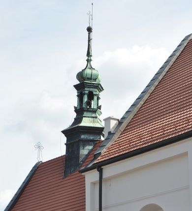 Zdjęcie nr 4: Kościół jest położony na wzgórzu w pobliżu centrum, przy ul. Brata Alojzego Kosiby. Od zachodu przed kościołem znajduje się dziedziniec i dawny cmentarz obwiedzione murem z bramkami i stacjami Męki Pańskiej. Z cmentarza wejście prowadzi do kościoła, a przez furtę na teren przyklasztorny i dalej do ogrodu klasztornego. Kościół wzniesiony jest z cegły, otynkowany. Świątynia jest orientowana, jednonawowa, z węższym prezbiterium, z kaplicą od północy i kruchtą od zachodu. Przy kościele od południa znajdują się zakrystia i zabudowania klasztorne. Prezbiterium na rzucie prostokąta, zamknięte od wschodu prostą ścianą, trójprzęsłowe, przekryte sklepieniem kolebkowym z przecinającymi się lunetami. W każdym przęśle ściany północnej wysoko umieszczone półkoliście zamknięte okna. Otworom okiennym odpowiadają tej samej wielkości nisze umieszczone w ścianie południowej. Wejście do klasztornego korytarza i zakrystii umieszczone jest w przęśle środkowym. Odpowiada mu otwór komunikacyjny po stronie przeciwnej. W przęśle zachodnim zlokalizowano drugie wejście do południowego korytarza klasztornego. Przestrzeń miedzy prezbiterium a korpusem zawężona arkadą tęczową, zamkniętą półkoliście. Korpus jednonawowy, szerszy z wnękami na ołtarze, czteroprzęsłowy, przekryty sklepieniem kolebkowym na gurtach z lunetami. Wnęka w trzecim przęśle od wschodu zamieniona na otwór do kaplicy północnej. Połowę przęsła zachodniego zajmuje empora muzyczna oparta na nisko schodzącym sklepieniu kolebkowym. Przy emporze, w ścianach wzdłużnych nawy, znacznie mniejsze, półkoliście zamknięte wnęki na konfesjonały. W lunetach, po obu stronach półkoliście zamknięte okna. Okna w przęśle zachodnim zastępują tej samej wielkości nisze. Główne wejście do kościoła w osi ściany zachodniej, zamknięte łukiem odcinkowym. W osi nad chórem muzycznym, półkoliście zamknięte okno, większe od pozostałych. Wejście do kościoła objęte prostokątnym portalem z piaskowca. Kaplica północna wzniesiona na planie kwadratu, przekryta sklepieniem współczesnym, zbliżonym w formie do klasztornego, zwieńczona latarnią. Okna, umieszczone w ścianie wschodniej i zachodniej, o tym samym wykroju utworzonym z wąskiego prostokąta przechodzącego górą w formę wachlarza lub wycinka koła. Zewnętrzne elewacje artykułuje podział osiowy i dekoracja lizenowo-ramowa, złożona z wydatnych elementów wertykalnych i horyzontalnych. Jednoosiową fasadę nad kruchtą ozdabia poniżej okna profilowany gzyms. Całość zamknięta wysoką, trójkątną ścianą szczytową, z trzema półkoliście zamkniętymi niszami. W nich polichromowane płaskorzeźby o kształcie stojącego prostokąta zamkniętego łukiem pełnym przedstawiające: stygmatyzację św. Franciszka, św. Piotra z Alkantary, św. Antoniego Padewskiego. Szczyt zwieńczony metalowym krzyżem osadzonym na niskim cokole. Kruchta przy fasadzie  z dwoma wejściami. Wejście zachodnie obejmuje półkoliście zamknięty portal z piaskowca, z dekoracją płycinową na węgarach, z kapitelami i skromnie profilowaną archiwoltą spiętą kluczem. Węższe wejście od północy z prostym, półkoliście zamkniętym portalem z piaskowca. Budowlę zamkniętą profilowanym gzymsem wieńczy trójkątny naczółek, przechodzący po bokach w balustradę z dekoracją płycinową. Na narożnych słupkach balustrady obeliskowe sterczyny. W półkoliście zamkniętej wnęce, umieszczonej pośrodku naczółka, wizerunek Matki Boskiej Nieustającej Pomocy. Wschodnia ściana prezbiterium, w dolnej partii zupełnie płaska, w górnej z triadą prostokątnych wnęk. Część szczytową oddziela od dolnej profilowany gzyms kryty dachówką. W osi trójkątnego szczytu wschodniego prostokątna wnęka z płaskorzeźbioną i polichromowaną sceną przedstawiającą św. Porcjunkulę w towarzystwie Chrystusa oraz św. Franciszka. Bryłę świątyni zamykają wysokie dachy dwuspadowe. Pośrodku dachu prezbiterium wieloboczna wieżyczka na sygnaturkę z ażurową latarnią. Bryłę kaplicy przekrywa dach czterospadowy. Ośmioboczną formę jej latarni zamyka dach wielospadowy zwieńczony metalowym krzyżem.