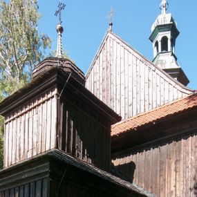 Zdjęcie nr 1: Kościół drewniany, orientowany, jednonawowy, wzniesiony na niewielkiej ceglanej podmurówce, o konstrukcji zrębowej, ściany szalowane pionowo z listowaniem, kruchta zachodnia o konstrukcji słupowo-ramowej. Nawa na rzucie prostokąta zbliżonego do kwadratu, prezbiterium węższe od nawy, wydłużone, zamknięte trójbocznie. Do północnej ściany prezbiterium przylega zakrystia na planie prostokąta. Do północnej ściany nawy przywiera niewielka kruchta na planie prostokąta, zamknięta trójbocznie. Przy zachodniej ścianie nawy znajduje się kruchta na rzucie prostokąta. Wnętrze nakryte pozornymi, spłaszczonymi sklepieniami o krzywiźnie przybierającej kształt łuku odcinkowego. Pomiędzy nawą a prezbiterium otwór tęczowy o wykroju prostokąta zbliżonego do kwadratu zamkniętego łukiem koszowym. Prezbiterium niższe od nawy, sięgające wysokości łuku tęczowego. Ściany prezbiterium i nawy obiega profilowany gzyms, oddzielający je od sklepień. W części zachodniej nawy parapet chóru muzycznego wsparty na dwóch kolumnach o stylizowanych kapitelach kompozytowych i kanelowanych trzonach na wysokich cokołach. W północno-zachodnim narożu drabiniaste schody prowadzące na chór w ośmiobocznej obudowie. Ściany i sklepienia pokryte polichromią. Na ścianach wzdłużnych oraz na osi ściany zachodniej otwory drzwiowe o prostokątnym wykroju zamknięte drzwiami spągowymi z desek oraz płycinowymi, na północnej ścianie prezbiterium prostokątny otwór drzwiowy do zakrystii. Posadzka z płyt kamiennych, szachownicowa. Kruchty i zakrystia nakryte stropami, przez nie dostęp do wnętrza. 
Elewacja frontowa jednoosiowa, zamknięta trójkątnym szczytem, poprzedzona kruchtą. Na osi wejście do kruchty zachodniej w postaci dwuskrzydłowych drzwi w formie stojącego prostokąta. Nad kruchtą pięterko dzwonowe z prostokątnym otworem zamykanym dwuskrzydłowymi okiennicami. Elewacja boczna południowa z czterema oknami, po dwa w nawie i prezbiterium. Elewacja północna przepruta dwoma oknami w części nawy. Okna krosnowe, w formie stojącego prostokąta, o niewielkich podziałach kwaterowych z witrażami. Na wschodniej ścianie kruchty północnej okno i jednoskrzydłowe drzwi. W zakrystii okno na ścianie północnej i drzwi jednoskrzydłowe na ścianie wschodniej. Kościół nakrywają dachy dwuspadowe, wyższy nad korpusem nawowym, niższy nad prezbiterium. Kruchta zachodnia w formie przysadzistej wieży, niższej od korpusu nawowego z pięterkiem dzwonowym, zwieńczonym hełmem baniastym, pokrytym gontem z iglicą oraz gałką i krzyżem. Kruchta północna z dachem wielospadowym. Zakrystia nakryta dachem pulpitowym. W połowie wysokości dachu znajduje się wieżyczka na sygnaturkę na ośmiobocznym obitym blachą trzonie, z ażurową latarnią nakrytą baniastym hełmem zakończonym kulą z krzyżem. 



