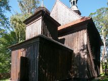 Zdjęcie nr 1: Kościół drewniany, orientowany, jednonawowy, wzniesiony na niewielkiej ceglanej podmurówce, o konstrukcji zrębowej, ściany szalowane pionowo z listowaniem, kruchta zachodnia o konstrukcji słupowo-ramowej. Nawa na rzucie prostokąta zbliżonego do kwadratu, prezbiterium węższe od nawy, wydłużone, zamknięte trójbocznie. Do północnej ściany prezbiterium przylega zakrystia na planie prostokąta. Do północnej ściany nawy przywiera niewielka kruchta na planie prostokąta, zamknięta trójbocznie. Przy zachodniej ścianie nawy znajduje się kruchta na rzucie prostokąta. Wnętrze nakryte pozornymi, spłaszczonymi sklepieniami o krzywiźnie przybierającej kształt łuku odcinkowego. Pomiędzy nawą a prezbiterium otwór tęczowy o wykroju prostokąta zbliżonego do kwadratu zamkniętego łukiem koszowym. Prezbiterium niższe od nawy, sięgające wysokości łuku tęczowego. Ściany prezbiterium i nawy obiega profilowany gzyms, oddzielający je od sklepień. W części zachodniej nawy parapet chóru muzycznego wsparty na dwóch kolumnach o stylizowanych kapitelach kompozytowych i kanelowanych trzonach na wysokich cokołach. W północno-zachodnim narożu drabiniaste schody prowadzące na chór w ośmiobocznej obudowie. Ściany i sklepienia pokryte polichromią. Na ścianach wzdłużnych oraz na osi ściany zachodniej otwory drzwiowe o prostokątnym wykroju zamknięte drzwiami spągowymi z desek oraz płycinowymi, na północnej ścianie prezbiterium prostokątny otwór drzwiowy do zakrystii. Posadzka z płyt kamiennych, szachownicowa. Kruchty i zakrystia nakryte stropami, przez nie dostęp do wnętrza. 
Elewacja frontowa jednoosiowa, zamknięta trójkątnym szczytem, poprzedzona kruchtą. Na osi wejście do kruchty zachodniej w postaci dwuskrzydłowych drzwi w formie stojącego prostokąta. Nad kruchtą pięterko dzwonowe z prostokątnym otworem zamykanym dwuskrzydłowymi okiennicami. Elewacja boczna południowa z czterema oknami, po dwa w nawie i prezbiterium. Elewacja północna przepruta dwoma oknami w części nawy. Okna krosnowe, w formie stojącego prostokąta, o niewielkich podziałach kwaterowych z witrażami. Na wschodniej ścianie kruchty północnej okno i jednoskrzydłowe drzwi. W zakrystii okno na ścianie północnej i drzwi jednoskrzydłowe na ścianie wschodniej. Kościół nakrywają dachy dwuspadowe, wyższy nad korpusem nawowym, niższy nad prezbiterium. Kruchta zachodnia w formie przysadzistej wieży, niższej od korpusu nawowego z pięterkiem dzwonowym, zwieńczonym hełmem baniastym, pokrytym gontem z iglicą oraz gałką i krzyżem. Kruchta północna z dachem wielospadowym. Zakrystia nakryta dachem pulpitowym. W połowie wysokości dachu znajduje się wieżyczka na sygnaturkę na ośmiobocznym obitym blachą trzonie, z ażurową latarnią nakrytą baniastym hełmem zakończonym kulą z krzyżem. 



