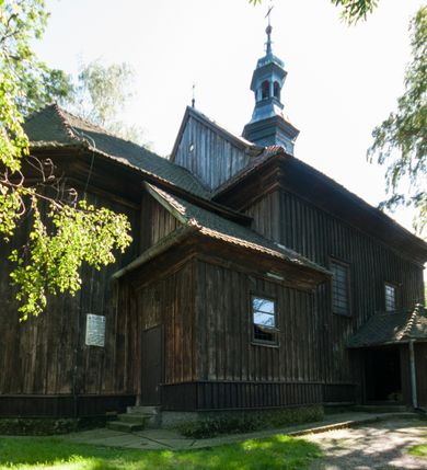 Zdjęcie nr 3: Kościół drewniany, orientowany, jednonawowy, wzniesiony na niewielkiej ceglanej podmurówce, o konstrukcji zrębowej, ściany szalowane pionowo z listowaniem, kruchta zachodnia o konstrukcji słupowo-ramowej. Nawa na rzucie prostokąta zbliżonego do kwadratu, prezbiterium węższe od nawy, wydłużone, zamknięte trójbocznie. Do północnej ściany prezbiterium przylega zakrystia na planie prostokąta. Do północnej ściany nawy przywiera niewielka kruchta na planie prostokąta, zamknięta trójbocznie. Przy zachodniej ścianie nawy znajduje się kruchta na rzucie prostokąta. Wnętrze nakryte pozornymi, spłaszczonymi sklepieniami o krzywiźnie przybierającej kształt łuku odcinkowego. Pomiędzy nawą a prezbiterium otwór tęczowy o wykroju prostokąta zbliżonego do kwadratu zamkniętego łukiem koszowym. Prezbiterium niższe od nawy, sięgające wysokości łuku tęczowego. Ściany prezbiterium i nawy obiega profilowany gzyms, oddzielający je od sklepień. W części zachodniej nawy parapet chóru muzycznego wsparty na dwóch kolumnach o stylizowanych kapitelach kompozytowych i kanelowanych trzonach na wysokich cokołach. W północno-zachodnim narożu drabiniaste schody prowadzące na chór w ośmiobocznej obudowie. Ściany i sklepienia pokryte polichromią. Na ścianach wzdłużnych oraz na osi ściany zachodniej otwory drzwiowe o prostokątnym wykroju zamknięte drzwiami spągowymi z desek oraz płycinowymi, na północnej ścianie prezbiterium prostokątny otwór drzwiowy do zakrystii. Posadzka z płyt kamiennych, szachownicowa. Kruchty i zakrystia nakryte stropami, przez nie dostęp do wnętrza. 
Elewacja frontowa jednoosiowa, zamknięta trójkątnym szczytem, poprzedzona kruchtą. Na osi wejście do kruchty zachodniej w postaci dwuskrzydłowych drzwi w formie stojącego prostokąta. Nad kruchtą pięterko dzwonowe z prostokątnym otworem zamykanym dwuskrzydłowymi okiennicami. Elewacja boczna południowa z czterema oknami, po dwa w nawie i prezbiterium. Elewacja północna przepruta dwoma oknami w części nawy. Okna krosnowe, w formie stojącego prostokąta, o niewielkich podziałach kwaterowych z witrażami. Na wschodniej ścianie kruchty północnej okno i jednoskrzydłowe drzwi. W zakrystii okno na ścianie północnej i drzwi jednoskrzydłowe na ścianie wschodniej. Kościół nakrywają dachy dwuspadowe, wyższy nad korpusem nawowym, niższy nad prezbiterium. Kruchta zachodnia w formie przysadzistej wieży, niższej od korpusu nawowego z pięterkiem dzwonowym, zwieńczonym hełmem baniastym, pokrytym gontem z iglicą oraz gałką i krzyżem. Kruchta północna z dachem wielospadowym. Zakrystia nakryta dachem pulpitowym. W połowie wysokości dachu znajduje się wieżyczka na sygnaturkę na ośmiobocznym obitym blachą trzonie, z ażurową latarnią nakrytą baniastym hełmem zakończonym kulą z krzyżem. 



