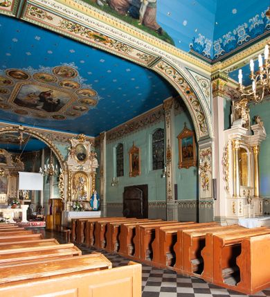 Zdjęcie nr 8: Kościół drewniany, orientowany, z dwuczęściowym korpusem: od wschodu jednonawowym, od zachodu trójnawowym; z prezbiterium zamkniętym trójbocznie, przy którym zakrystia od północy, z przybudówką od południa i dwiema wieżami od zachodu. Od wschodu chór muzyczny wbudowany pomiędzy wieże. Kościół wzniesiono w konstrukcji zrębowej, wieże w słupowo-ramowej, ściany oszalowane pionowym listwowaniem. 
Ściany prezbiterium i wschodniej części korpusu podzielone pseudokolumnami, zachodnia część podzielona kolumnami dźwigającymi architraw. Prezbiterium oddziela półokrągły łuk tęczowy; wschodnią i zachodnią część nawy łuk spłaszczony. Wschodnią część nawy oraz nawy boczne części zachodniej przekrywa płaski strop, zachodnią pozorne sklepienie zwierciadlane. Ściany oraz stropy pokryte polichromią figuralną, ornamentalną oraz roślinną: w prezbiterium namalowano wizerunek Ukrzyżowanego Chrystusa, przed łukiem tęczowym Matkę Boską w otoczeniu tajemnic różańcowych. Strop nawy imituje gwiaździste niebo. Posadzka kamienna. Wejście główne od zachodu, dwoje drzwi spod wież, kolejne od południa, przez przedsionek (babiniec), do zakrystii prowadzi portal zamknięty łukiem nadwieszonym. Cztery okna w prezbiterium o wykroju prostokątnym zamkniętym łukiem nadwieszonym, cztery we wschodniej części nawy o takim samym kształcie, cztery w zachodniej części zamknięte podwójnym łukiem kotarowym, dwa w zakrystii, południowej przybudówce, po dwa wysokie, wąskie okna w wieżach. Fasada dwuwieżowa, trójosiowa, trójkondygnacyjna. Przed wejściem kruchta zwieńczona dachem dwuspadowym, do której prowadzą dwuskrzydłowe drzwi w kształcie prostokątów, ściany boczne przeprute oknami. Powyżej dwie gładkie kondygnacje przedzielone dachem pulpitowym. Wieże trójkondygnacyjne, w dolnej kondygnacji drzwi, w wyższej okna w kształcie stojących prostokątów zamkniętych łukiem ostrym z wyciętym od dołu fragmentem pięcioliścia, powyżej ażurowa koronka. Ostatnią kondygnację tworzy izbica z nadwieszonym gankiem zamkniętym łukami spłaszczonymi. Od zewnątrz wyraźny podział na bryły, ściany gładkie. Każdą część przykrywa gontowy dach dwuspadowy, wspólny dla prezbiterium i starszej części, osobny dla nowszej części nawy; wieże nakryte hełmami namiotowymi, na kalenicy nawy baniasta wieżyczka na sygnaturkę z latarnią.  