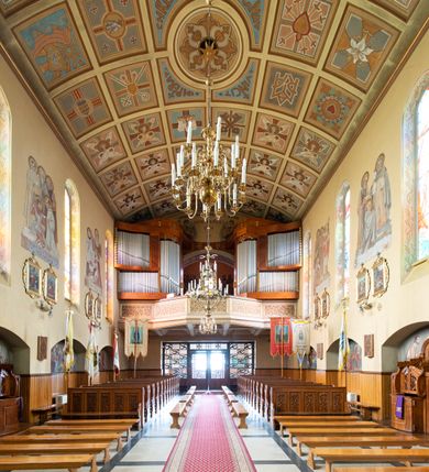 Zdjęcie nr 15: Kościół jest budowlą orientowaną, założoną na planie wydłużonego prostokąta, murowaną, jednonawową z prezbiterium i zakrystią (od północy). Prezbiterium jest węższe od nawy, zamknięte wielobocznie, oddziela je tęcza o łuku półkolistym. Od zachodu chór zamknięty balustradą załamaną trójbocznie i wysuniętą przed lico w części środkowej, dekorowaną płycinami z wicią roślinną. Ściany wnętrza gładkie, brak podziałów pionowych, poziomy podział tworzą przy ziemi nisze zamknięte łukiem odcinkowym; dół ścian wyłożony drewnianą boazerią. Ściany przeprute oknami – prezbiterium dwoma, nawa ośmioma w kształcie stojącego prostokąta zamkniętego łukiem półkolistym; większość wypełniają witraże. Cztery okna w zakrystii. Główne wejście przez korpus wieżowy od zachodu, drugie od zakrystii. Elewacje kościoła są gładkie, górne partie z cegieł, dolne oraz naroża podkreślone okładziną kamienną. Wokół, poniżej partii okien kapnik. Wieża z wejściem umieszczonym w glifie w kształcie stojącego prostokąta zamkniętego łukiem odcinkowym, chronionym daszkiem, ponad którym niewielkie okno. W górnej partii z każdej strony małe okno, pod dachem arkady zamknięte półkoliście, po trzy na każdą stronę. Środkowa arkada ściany frontowej przysłonięta tarczą zegara. Dach nawy dwuspadowy, prezbiterium i zakrystii wieloboczny, ponad nawą kamienna wieżyczka na sygnaturkę, wieża przekryta hełmem namiotowym. Od zewnątrz, na wschodniej ścianie prezbiterium figura ukrzyżowanego Jezusa. Najcenniejszym zabytkiem kościoła jest siedemnastowieczny ołtarz główny, który w poprzedniej budowli stanowił ołtarz boczny. Polichromię zaprojektowała Jadwiga Rymar z Krakowa.