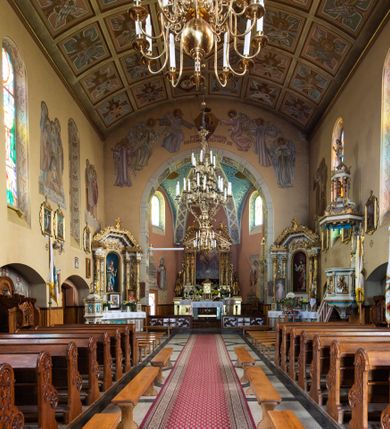 Zdjęcie nr 11: Kościół jest budowlą orientowaną, założoną na planie wydłużonego prostokąta, murowaną, jednonawową z prezbiterium i zakrystią (od północy). Prezbiterium jest węższe od nawy, zamknięte wielobocznie, oddziela je tęcza o łuku półkolistym. Od zachodu chór zamknięty balustradą załamaną trójbocznie i wysuniętą przed lico w części środkowej, dekorowaną płycinami z wicią roślinną. Ściany wnętrza gładkie, brak podziałów pionowych, poziomy podział tworzą przy ziemi nisze zamknięte łukiem odcinkowym; dół ścian wyłożony drewnianą boazerią. Ściany przeprute oknami – prezbiterium dwoma, nawa ośmioma w kształcie stojącego prostokąta zamkniętego łukiem półkolistym; większość wypełniają witraże. Cztery okna w zakrystii. Główne wejście przez korpus wieżowy od zachodu, drugie od zakrystii. Elewacje kościoła są gładkie, górne partie z cegieł, dolne oraz naroża podkreślone okładziną kamienną. Wokół, poniżej partii okien kapnik. Wieża z wejściem umieszczonym w glifie w kształcie stojącego prostokąta zamkniętego łukiem odcinkowym, chronionym daszkiem, ponad którym niewielkie okno. W górnej partii z każdej strony małe okno, pod dachem arkady zamknięte półkoliście, po trzy na każdą stronę. Środkowa arkada ściany frontowej przysłonięta tarczą zegara. Dach nawy dwuspadowy, prezbiterium i zakrystii wieloboczny, ponad nawą kamienna wieżyczka na sygnaturkę, wieża przekryta hełmem namiotowym. Od zewnątrz, na wschodniej ścianie prezbiterium figura ukrzyżowanego Jezusa. Najcenniejszym zabytkiem kościoła jest siedemnastowieczny ołtarz główny, który w poprzedniej budowli stanowił ołtarz boczny. Polichromię zaprojektowała Jadwiga Rymar z Krakowa.