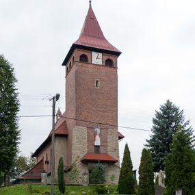 Zdjęcie nr 1: Kościół jest budowlą orientowaną, założoną na planie wydłużonego prostokąta, murowaną, jednonawową z prezbiterium i zakrystią (od północy). Prezbiterium jest węższe od nawy, zamknięte wielobocznie, oddziela je tęcza o łuku półkolistym. Od zachodu chór zamknięty balustradą załamaną trójbocznie i wysuniętą przed lico w części środkowej, dekorowaną płycinami z wicią roślinną. Ściany wnętrza gładkie, brak podziałów pionowych, poziomy podział tworzą przy ziemi nisze zamknięte łukiem odcinkowym; dół ścian wyłożony drewnianą boazerią. Ściany przeprute oknami – prezbiterium dwoma, nawa ośmioma w kształcie stojącego prostokąta zamkniętego łukiem półkolistym; większość wypełniają witraże. Cztery okna w zakrystii. Główne wejście przez korpus wieżowy od zachodu, drugie od zakrystii. Elewacje kościoła są gładkie, górne partie z cegieł, dolne oraz naroża podkreślone okładziną kamienną. Wokół, poniżej partii okien kapnik. Wieża z wejściem umieszczonym w glifie w kształcie stojącego prostokąta zamkniętego łukiem odcinkowym, chronionym daszkiem, ponad którym niewielkie okno. W górnej partii z każdej strony małe okno, pod dachem arkady zamknięte półkoliście, po trzy na każdą stronę. Środkowa arkada ściany frontowej przysłonięta tarczą zegara. Dach nawy dwuspadowy, prezbiterium i zakrystii wieloboczny, ponad nawą kamienna wieżyczka na sygnaturkę, wieża przekryta hełmem namiotowym. Od zewnątrz, na wschodniej ścianie prezbiterium figura ukrzyżowanego Jezusa. Najcenniejszym zabytkiem kościoła jest siedemnastowieczny ołtarz główny, który w poprzedniej budowli stanowił ołtarz boczny. Polichromię zaprojektowała Jadwiga Rymar z Krakowa.