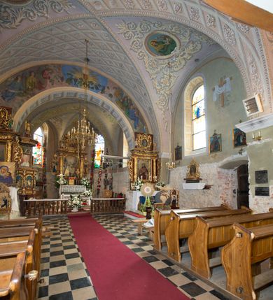 Zdjęcie nr 4: Kościół położony jest na wzniesieniu, obwiedziony dookoła niskim murem. Świątynia murowana, orientowana, jednonawowa na planie prostokątnej nawy z węższym prezbiterium zamkniętym półkoliście, z wieżą od zachodu; przykryty wysokim dwuspadowym dachem, z sygnaturką nad prezbiterium. Wieża czworoboczna, w przyziemiu mieszcząca kruchtę, wyżej przechodząca w ośmiobok, zwieńczona stylizowanym na gotycki, iglicowym, pokrytym blachą hełmem, flankowanym trójkątnymi szczycikami. Od południa kościoła usytuowana jest druga kruchta z kamiennym portalem, a od północy zakrystia z dodatkowym pomieszczeniem na paramenty liturgiczne, nad nimi empora. Prezbiterium oraz nawę obejmuje z zewnątrz sześć wysokich skarp. Wewnątrz podziały architektoniczne wydzielają przyścienne filary w nawie z silnie wysuniętym do wnętrza łukiem tęczy. Prezbiterium oraz nawę oświetla pięć wysokich okien, zamkniętych półkoliście, usytuowanych od południa. Portal główny wykonany z wapienia pińczowskiego o typie arkadowym z charakterystycznym układem kamiennych ciosów dźwiga boniowany łuk archiwolty. Nad nim trójkątny przyczółek, silnie wysunięty przed lico ściany, ujęty dookoła wydatnym, profilowanym gzymsem z kartuszem w polu z herbami: Lubicz, Leliwa, Junosza i Rawicz oraz inicjałami „ALDL” i datą „An[n]o D[omi]ni 1623”. Portal południowy z wapienia jurajskiego o wykroju zbliżonym do ostrołukowego (krzywo wycięty). Natomiast portal do zakrystii o renesansowej budowie i dekoracji. Nawa sklepiona krzyżowo-kolebkowo.
Do zewnętrznej, południowej ściany kościoła dostawiony jest pomnik nagrobny hrabiego Jakuba z Granowa i Eleonory z Dembowskich Wodzickich.
