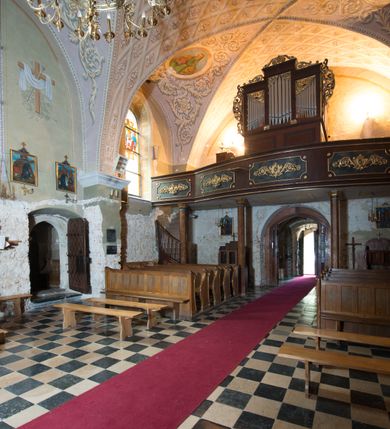 Zdjęcie nr 9: Kościół położony jest na wzniesieniu, obwiedziony dookoła niskim murem. Świątynia murowana, orientowana, jednonawowa na planie prostokątnej nawy z węższym prezbiterium zamkniętym półkoliście, z wieżą od zachodu; przykryty wysokim dwuspadowym dachem, z sygnaturką nad prezbiterium. Wieża czworoboczna, w przyziemiu mieszcząca kruchtę, wyżej przechodząca w ośmiobok, zwieńczona stylizowanym na gotycki, iglicowym, pokrytym blachą hełmem, flankowanym trójkątnymi szczycikami. Od południa kościoła usytuowana jest druga kruchta z kamiennym portalem, a od północy zakrystia z dodatkowym pomieszczeniem na paramenty liturgiczne, nad nimi empora. Prezbiterium oraz nawę obejmuje z zewnątrz sześć wysokich skarp. Wewnątrz podziały architektoniczne wydzielają przyścienne filary w nawie z silnie wysuniętym do wnętrza łukiem tęczy. Prezbiterium oraz nawę oświetla pięć wysokich okien, zamkniętych półkoliście, usytuowanych od południa. Portal główny wykonany z wapienia pińczowskiego o typie arkadowym z charakterystycznym układem kamiennych ciosów dźwiga boniowany łuk archiwolty. Nad nim trójkątny przyczółek, silnie wysunięty przed lico ściany, ujęty dookoła wydatnym, profilowanym gzymsem z kartuszem w polu z herbami: Lubicz, Leliwa, Junosza i Rawicz oraz inicjałami „ALDL” i datą „An[n]o D[omi]ni 1623”. Portal południowy z wapienia jurajskiego o wykroju zbliżonym do ostrołukowego (krzywo wycięty). Natomiast portal do zakrystii o renesansowej budowie i dekoracji. Nawa sklepiona krzyżowo-kolebkowo.
Do zewnętrznej, południowej ściany kościoła dostawiony jest pomnik nagrobny hrabiego Jakuba z Granowa i Eleonory z Dembowskich Wodzickich.