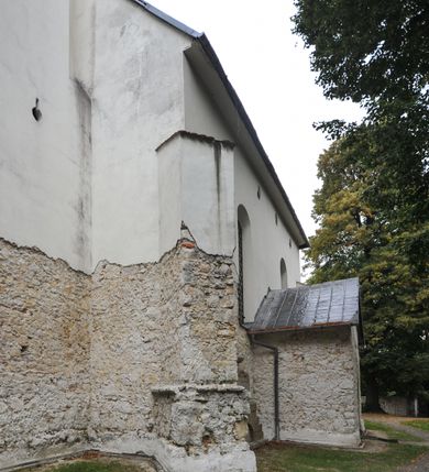 Zdjęcie nr 14: Kościół położony jest na wzniesieniu, obwiedziony dookoła niskim murem. Świątynia murowana, orientowana, jednonawowa na planie prostokątnej nawy z węższym prezbiterium zamkniętym półkoliście, z wieżą od zachodu; przykryty wysokim dwuspadowym dachem, z sygnaturką nad prezbiterium. Wieża czworoboczna, w przyziemiu mieszcząca kruchtę, wyżej przechodząca w ośmiobok, zwieńczona stylizowanym na gotycki, iglicowym, pokrytym blachą hełmem, flankowanym trójkątnymi szczycikami. Od południa kościoła usytuowana jest druga kruchta z kamiennym portalem, a od północy zakrystia z dodatkowym pomieszczeniem na paramenty liturgiczne, nad nimi empora. Prezbiterium oraz nawę obejmuje z zewnątrz sześć wysokich skarp. Wewnątrz podziały architektoniczne wydzielają przyścienne filary w nawie z silnie wysuniętym do wnętrza łukiem tęczy. Prezbiterium oraz nawę oświetla pięć wysokich okien, zamkniętych półkoliście, usytuowanych od południa. Portal główny wykonany z wapienia pińczowskiego o typie arkadowym z charakterystycznym układem kamiennych ciosów dźwiga boniowany łuk archiwolty. Nad nim trójkątny przyczółek, silnie wysunięty przed lico ściany, ujęty dookoła wydatnym, profilowanym gzymsem z kartuszem w polu z herbami: Lubicz, Leliwa, Junosza i Rawicz oraz inicjałami „ALDL” i datą „An[n]o D[omi]ni 1623”. Portal południowy z wapienia jurajskiego o wykroju zbliżonym do ostrołukowego (krzywo wycięty). Natomiast portal do zakrystii o renesansowej budowie i dekoracji. Nawa sklepiona krzyżowo-kolebkowo.
Do zewnętrznej, południowej ściany kościoła dostawiony jest pomnik nagrobny hrabiego Jakuba z Granowa i Eleonory z Dembowskich Wodzickich.