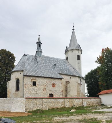 Zdjęcie nr 10: Kościół położony jest na wzniesieniu, obwiedziony dookoła niskim murem. Świątynia murowana, orientowana, jednonawowa na planie prostokątnej nawy z węższym prezbiterium zamkniętym półkoliście, z wieżą od zachodu; przykryty wysokim dwuspadowym dachem, z sygnaturką nad prezbiterium. Wieża czworoboczna, w przyziemiu mieszcząca kruchtę, wyżej przechodząca w ośmiobok, zwieńczona stylizowanym na gotycki, iglicowym, pokrytym blachą hełmem, flankowanym trójkątnymi szczycikami. Od południa kościoła usytuowana jest druga kruchta z kamiennym portalem, a od północy zakrystia z dodatkowym pomieszczeniem na paramenty liturgiczne, nad nimi empora. Prezbiterium oraz nawę obejmuje z zewnątrz sześć wysokich skarp. Wewnątrz podziały architektoniczne wydzielają przyścienne filary w nawie z silnie wysuniętym do wnętrza łukiem tęczy. Prezbiterium oraz nawę oświetla pięć wysokich okien, zamkniętych półkoliście, usytuowanych od południa. Portal główny wykonany z wapienia pińczowskiego o typie arkadowym z charakterystycznym układem kamiennych ciosów dźwiga boniowany łuk archiwolty. Nad nim trójkątny przyczółek, silnie wysunięty przed lico ściany, ujęty dookoła wydatnym, profilowanym gzymsem z kartuszem w polu z herbami: Lubicz, Leliwa, Junosza i Rawicz oraz inicjałami „ALDL” i datą „An[n]o D[omi]ni 1623”. Portal południowy z wapienia jurajskiego o wykroju zbliżonym do ostrołukowego (krzywo wycięty). Natomiast portal do zakrystii o renesansowej budowie i dekoracji. Nawa sklepiona krzyżowo-kolebkowo.
Do zewnętrznej, południowej ściany kościoła dostawiony jest pomnik nagrobny hrabiego Jakuba z Granowa i Eleonory z Dembowskich Wodzickich.