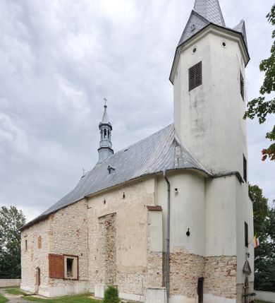 Zdjęcie nr 1: Kościół położony jest na wzniesieniu, obwiedziony dookoła niskim murem. Świątynia murowana, orientowana, jednonawowa na planie prostokątnej nawy z węższym prezbiterium zamkniętym półkoliście, z wieżą od zachodu; przykryty wysokim dwuspadowym dachem, z sygnaturką nad prezbiterium. Wieża czworoboczna, w przyziemiu mieszcząca kruchtę, wyżej przechodząca w ośmiobok, zwieńczona stylizowanym na gotycki, iglicowym, pokrytym blachą hełmem, flankowanym trójkątnymi szczycikami. Od południa kościoła usytuowana jest druga kruchta z kamiennym portalem, a od północy zakrystia z dodatkowym pomieszczeniem na paramenty liturgiczne, nad nimi empora. Prezbiterium oraz nawę obejmuje z zewnątrz sześć wysokich skarp. Wewnątrz podziały architektoniczne wydzielają przyścienne filary w nawie z silnie wysuniętym do wnętrza łukiem tęczy. Prezbiterium oraz nawę oświetla pięć wysokich okien, zamkniętych półkoliście, usytuowanych od południa. Portal główny wykonany z wapienia pińczowskiego o typie arkadowym z charakterystycznym układem kamiennych ciosów dźwiga boniowany łuk archiwolty. Nad nim trójkątny przyczółek, silnie wysunięty przed lico ściany, ujęty dookoła wydatnym, profilowanym gzymsem z kartuszem w polu z herbami: Lubicz, Leliwa, Junosza i Rawicz oraz inicjałami „ALDL” i datą „An[n]o D[omi]ni 1623”. Portal południowy z wapienia jurajskiego o wykroju zbliżonym do ostrołukowego (krzywo wycięty). Natomiast portal do zakrystii o renesansowej budowie i dekoracji. Nawa sklepiona krzyżowo-kolebkowo.
Do zewnętrznej, południowej ściany kościoła dostawiony jest pomnik nagrobny hrabiego Jakuba z Granowa i Eleonory z Dembowskich Wodzickich.