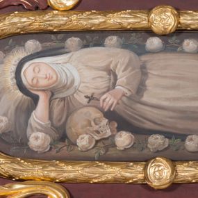 Zdjęcie nr 1: Obraz w kształcie leżącego owalu z przedstawieniem św. Rozalii. W centrum całopostaciowe przedstawienie św. Rozalii leżącej w grocie z głową z lewej strony obrazu, wspartą prawą ręką, ugiętą w łokciu, w lewej trzyma mały krucyfiks. Twarz o młodzieńczych rysach z zamkniętymi oczami, z długim nosem i ustami ułożonymi w delikatny uśmiech, karnacja jasna. Święta ubrana w jasnoszary habit z czarnym welonem, stopy bose, na głowie wieniec z białych róż, a wokół głowy promienisty nimb. U dołu obrazu, bliżej lewej strony leży czaszka. Święta otoczona jest wieńcem z gałązek białych róż. Rama złocona w formie wieńca z liści wawrzynu i zdobiona czterema małymi różami.