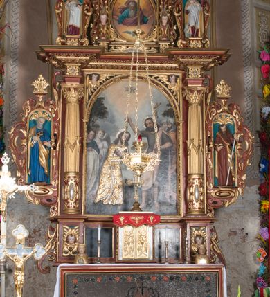Zdjęcie nr 11: Nastawa ołtarzowa architektoniczna, jednoosiowa, dwukondygnacyjna, na cokole. Ołtarz murowany z kamienną mensą. Na lewym boku ołtarza drewniana wnęka na oleje święte z inskrypcją „OLEA SACRA”. Antepedium w formie leżącego prostokąta w profilowanej ramie, pole kompozycyjne dekorowane dookoła rzędem kolorowych rombów. W polu antepedium znajduje się haftowane koralikami przedstawienie gorejącego serca w koronie cierniowej z zatkniętym u góry krzyżykiem łacińskim. Tabernakulum w formie prostopadłościennej skrzynki. Drzwiczki dwuskrzydłowe, odlewane, w polach przedstawienie wici roślinnej oraz litery alfa i omega. Ściany boczne zdobione kaboszonem i ornamentem małżowinowo-chrząstkowym. Nastawa ustawiona jest na cokole. Pierwsza kondygnacja ujęta parą kolumn. Podpory dźwigają pełne belkowanie wyłamane nad polem środkowym, zamknięte silnie wysuniętym gzymsem. Pole obrazowe w formie arkady z obrazem przedstawiającym Chrzest Chrystusa, na zasuwie obraz Matki Boskiej Nieustającej Pomocy. Kondygnacja ujęta jest uszami z płytkimi niszami dla figur św. Piotra po lewej stronie i św. Pawła po prawej, zwieńczonymi akroterionami utworzonymi z ornamentu małżowinowo-chrząstkowego. Druga kondygnacja ustawiona jest na cokole, ujęta pilastrami hermowymi o kapitelach korynckich, dźwigającymi pełne belkowanie z silnie wystającym gzymsem. Pole obrazowe w formie owalu z przedstawieniem Boga Ojca i Gołębicy Ducha Świętego. Po bokach drugiej kondygnacji znajdują się nisze z figurami św. Stanisława po prawej stronie i nierozpoznanego świętego biskupa po lewej. Ołtarz zwieńczony  jest cokołem z figurą św. Wojciecha.

Cokoły kolumn pierwszej kondygnacji dekorowane są z frontu uskrzydlonymi główkami anielskimi, na zewnętrznych bokach kartuszami z tarczą herbową czteropolową z herbami: Lubicz, Leliwa, Junosza i Rawicz; od wewnątrz ornamentem małżowinowym z chrząstką i kaboszonem. Cokoły kolumn pierwszej kondygnacji w jednej trzeciej wysokości zdobione są ornamentem małżowinowym z kaboszonami, powyżej trzon otoczony jest podwiązaną tkaniną. W polu środkowym w przyłuczach arkady umieszczone są uskrzydlone główki anielskie; węgary od wewnątrz dekorowane są kaboszonami z małżowiną oraz rozetami, podłucze zaś rozetami. Fryz zdobiony jest kaboszonami z małżowiną; a gzyms dekoracją roślinno-geometryczną. Uszy z niszami utworzone są z ornamentu małżowinowo-chrząstkowego. Cokół drugiej kondygnacji dekorowany jest ornamentem małżowinowo-chrząstkowym i kaboszonem, a trzony kolumn utworzone są uskrzydlonych główek anielskich o stylizowanych na woluty skrzydłach. W czterech narożach pola obrazowego umieszczone są uskrzydlone główki anielskie. W polu fryzu znajduje się uskrzydlona główka anielska; gzyms dekorowany jest ornamentem roślinnym. Kondygnacja ujęta jest uszami z płaskiej małżowiny. Gzyms zakończony ażurowym ornamentem małżowinowo-chrząstkowym. Nisze z figurami otoczone są ornamentem małżowinowo-chrząstkowym i zwieńczone cokołami z palmetą. 
Nastawa polichromowana na czerwono z zielonymi i czarnymi elementami. Ornamentyka i kolumny złocone, kaboszony srebrzone.