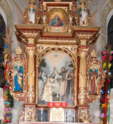 Zdjęcie nr 1: Nastawa ołtarzowa architektoniczna, jednoosiowa, dwukondygnacyjna, na cokole. Ołtarz murowany z kamienną mensą. Na lewym boku ołtarza drewniana wnęka na oleje święte z inskrypcją „OLEA SACRA”. Antepedium w formie leżącego prostokąta w profilowanej ramie, pole kompozycyjne dekorowane dookoła rzędem kolorowych rombów. W polu antepedium znajduje się haftowane koralikami przedstawienie gorejącego serca w koronie cierniowej z zatkniętym u góry krzyżykiem łacińskim. Tabernakulum w formie prostopadłościennej skrzynki. Drzwiczki dwuskrzydłowe, odlewane, w polach przedstawienie wici roślinnej oraz litery alfa i omega. Ściany boczne zdobione kaboszonem i ornamentem małżowinowo-chrząstkowym. Nastawa ustawiona jest na cokole. Pierwsza kondygnacja ujęta parą kolumn. Podpory dźwigają pełne belkowanie wyłamane nad polem środkowym, zamknięte silnie wysuniętym gzymsem. Pole obrazowe w formie arkady z obrazem przedstawiającym Chrzest Chrystusa, na zasuwie obraz Matki Boskiej Nieustającej Pomocy. Kondygnacja ujęta jest uszami z płytkimi niszami dla figur św. Piotra po lewej stronie i św. Pawła po prawej, zwieńczonymi akroterionami utworzonymi z ornamentu małżowinowo-chrząstkowego. Druga kondygnacja ustawiona jest na cokole, ujęta pilastrami hermowymi o kapitelach korynckich, dźwigającymi pełne belkowanie z silnie wystającym gzymsem. Pole obrazowe w formie owalu z przedstawieniem Boga Ojca i Gołębicy Ducha Świętego. Po bokach drugiej kondygnacji znajdują się nisze z figurami św. Stanisława po prawej stronie i nierozpoznanego świętego biskupa po lewej. Ołtarz zwieńczony  jest cokołem z figurą św. Wojciecha.

Cokoły kolumn pierwszej kondygnacji dekorowane są z frontu uskrzydlonymi główkami anielskimi, na zewnętrznych bokach kartuszami z tarczą herbową czteropolową z herbami: Lubicz, Leliwa, Junosza i Rawicz; od wewnątrz ornamentem małżowinowym z chrząstką i kaboszonem. Cokoły kolumn pierwszej kondygnacji w jednej trzeciej wysokości zdobione są ornamentem małżowinowym z kaboszonami, powyżej trzon otoczony jest podwiązaną tkaniną. W polu środkowym w przyłuczach arkady umieszczone są uskrzydlone główki anielskie; węgary od wewnątrz dekorowane są kaboszonami z małżowiną oraz rozetami, podłucze zaś rozetami. Fryz zdobiony jest kaboszonami z małżowiną; a gzyms dekoracją roślinno-geometryczną. Uszy z niszami utworzone są z ornamentu małżowinowo-chrząstkowego. Cokół drugiej kondygnacji dekorowany jest ornamentem małżowinowo-chrząstkowym i kaboszonem, a trzony kolumn utworzone są uskrzydlonych główek anielskich o stylizowanych na woluty skrzydłach. W czterech narożach pola obrazowego umieszczone są uskrzydlone główki anielskie. W polu fryzu znajduje się uskrzydlona główka anielska; gzyms dekorowany jest ornamentem roślinnym. Kondygnacja ujęta jest uszami z płaskiej małżowiny. Gzyms zakończony ażurowym ornamentem małżowinowo-chrząstkowym. Nisze z figurami otoczone są ornamentem małżowinowo-chrząstkowym i zwieńczone cokołami z palmetą. 
Nastawa polichromowana na czerwono z zielonymi i czarnymi elementami. Ornamentyka i kolumny złocone, kaboszony srebrzone.