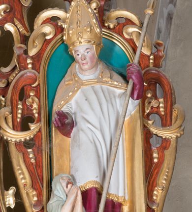 Zdjęcie nr 3: Nastawa ołtarzowa architektoniczna, jednoosiowa, dwukondygnacyjna, na cokole. Ołtarz murowany z kamienną mensą. Na lewym boku ołtarza drewniana wnęka na oleje święte z inskrypcją „OLEA SACRA”. Antepedium w formie leżącego prostokąta w profilowanej ramie, pole kompozycyjne dekorowane dookoła rzędem kolorowych rombów. W polu antepedium znajduje się haftowane koralikami przedstawienie gorejącego serca w koronie cierniowej z zatkniętym u góry krzyżykiem łacińskim. Tabernakulum w formie prostopadłościennej skrzynki. Drzwiczki dwuskrzydłowe, odlewane, w polach przedstawienie wici roślinnej oraz litery alfa i omega. Ściany boczne zdobione kaboszonem i ornamentem małżowinowo-chrząstkowym. Nastawa ustawiona jest na cokole. Pierwsza kondygnacja ujęta parą kolumn. Podpory dźwigają pełne belkowanie wyłamane nad polem środkowym, zamknięte silnie wysuniętym gzymsem. Pole obrazowe w formie arkady z obrazem przedstawiającym Chrzest Chrystusa, na zasuwie obraz Matki Boskiej Nieustającej Pomocy. Kondygnacja ujęta jest uszami z płytkimi niszami dla figur św. Piotra po lewej stronie i św. Pawła po prawej, zwieńczonymi akroterionami utworzonymi z ornamentu małżowinowo-chrząstkowego. Druga kondygnacja ustawiona jest na cokole, ujęta pilastrami hermowymi o kapitelach korynckich, dźwigającymi pełne belkowanie z silnie wystającym gzymsem. Pole obrazowe w formie owalu z przedstawieniem Boga Ojca i Gołębicy Ducha Świętego. Po bokach drugiej kondygnacji znajdują się nisze z figurami św. Stanisława po prawej stronie i nierozpoznanego świętego biskupa po lewej. Ołtarz zwieńczony  jest cokołem z figurą św. Wojciecha.

Cokoły kolumn pierwszej kondygnacji dekorowane są z frontu uskrzydlonymi główkami anielskimi, na zewnętrznych bokach kartuszami z tarczą herbową czteropolową z herbami: Lubicz, Leliwa, Junosza i Rawicz; od wewnątrz ornamentem małżowinowym z chrząstką i kaboszonem. Cokoły kolumn pierwszej kondygnacji w jednej trzeciej wysokości zdobione są ornamentem małżowinowym z kaboszonami, powyżej trzon otoczony jest podwiązaną tkaniną. W polu środkowym w przyłuczach arkady umieszczone są uskrzydlone główki anielskie; węgary od wewnątrz dekorowane są kaboszonami z małżowiną oraz rozetami, podłucze zaś rozetami. Fryz zdobiony jest kaboszonami z małżowiną; a gzyms dekoracją roślinno-geometryczną. Uszy z niszami utworzone są z ornamentu małżowinowo-chrząstkowego. Cokół drugiej kondygnacji dekorowany jest ornamentem małżowinowo-chrząstkowym i kaboszonem, a trzony kolumn utworzone są uskrzydlonych główek anielskich o stylizowanych na woluty skrzydłach. W czterech narożach pola obrazowego umieszczone są uskrzydlone główki anielskie. W polu fryzu znajduje się uskrzydlona główka anielska; gzyms dekorowany jest ornamentem roślinnym. Kondygnacja ujęta jest uszami z płaskiej małżowiny. Gzyms zakończony ażurowym ornamentem małżowinowo-chrząstkowym. Nisze z figurami otoczone są ornamentem małżowinowo-chrząstkowym i zwieńczone cokołami z palmetą. 
Nastawa polichromowana na czerwono z zielonymi i czarnymi elementami. Ornamentyka i kolumny złocone, kaboszony srebrzone.