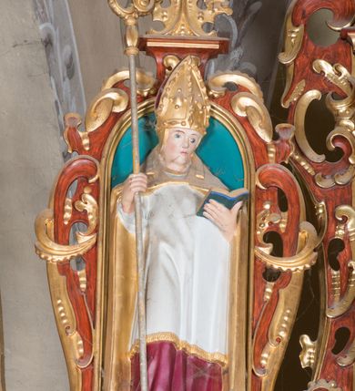 Zdjęcie nr 18: Nastawa ołtarzowa architektoniczna, jednoosiowa, dwukondygnacyjna, na cokole. Ołtarz murowany z kamienną mensą. Na lewym boku ołtarza drewniana wnęka na oleje święte z inskrypcją „OLEA SACRA”. Antepedium w formie leżącego prostokąta w profilowanej ramie, pole kompozycyjne dekorowane dookoła rzędem kolorowych rombów. W polu antepedium znajduje się haftowane koralikami przedstawienie gorejącego serca w koronie cierniowej z zatkniętym u góry krzyżykiem łacińskim. Tabernakulum w formie prostopadłościennej skrzynki. Drzwiczki dwuskrzydłowe, odlewane, w polach przedstawienie wici roślinnej oraz litery alfa i omega. Ściany boczne zdobione kaboszonem i ornamentem małżowinowo-chrząstkowym. Nastawa ustawiona jest na cokole. Pierwsza kondygnacja ujęta parą kolumn. Podpory dźwigają pełne belkowanie wyłamane nad polem środkowym, zamknięte silnie wysuniętym gzymsem. Pole obrazowe w formie arkady z obrazem przedstawiającym Chrzest Chrystusa, na zasuwie obraz Matki Boskiej Nieustającej Pomocy. Kondygnacja ujęta jest uszami z płytkimi niszami dla figur św. Piotra po lewej stronie i św. Pawła po prawej, zwieńczonymi akroterionami utworzonymi z ornamentu małżowinowo-chrząstkowego. Druga kondygnacja ustawiona jest na cokole, ujęta pilastrami hermowymi o kapitelach korynckich, dźwigającymi pełne belkowanie z silnie wystającym gzymsem. Pole obrazowe w formie owalu z przedstawieniem Boga Ojca i Gołębicy Ducha Świętego. Po bokach drugiej kondygnacji znajdują się nisze z figurami św. Stanisława po prawej stronie i nierozpoznanego świętego biskupa po lewej. Ołtarz zwieńczony  jest cokołem z figurą św. Wojciecha.

Cokoły kolumn pierwszej kondygnacji dekorowane są z frontu uskrzydlonymi główkami anielskimi, na zewnętrznych bokach kartuszami z tarczą herbową czteropolową z herbami: Lubicz, Leliwa, Junosza i Rawicz; od wewnątrz ornamentem małżowinowym z chrząstką i kaboszonem. Cokoły kolumn pierwszej kondygnacji w jednej trzeciej wysokości zdobione są ornamentem małżowinowym z kaboszonami, powyżej trzon otoczony jest podwiązaną tkaniną. W polu środkowym w przyłuczach arkady umieszczone są uskrzydlone główki anielskie; węgary od wewnątrz dekorowane są kaboszonami z małżowiną oraz rozetami, podłucze zaś rozetami. Fryz zdobiony jest kaboszonami z małżowiną; a gzyms dekoracją roślinno-geometryczną. Uszy z niszami utworzone są z ornamentu małżowinowo-chrząstkowego. Cokół drugiej kondygnacji dekorowany jest ornamentem małżowinowo-chrząstkowym i kaboszonem, a trzony kolumn utworzone są uskrzydlonych główek anielskich o stylizowanych na woluty skrzydłach. W czterech narożach pola obrazowego umieszczone są uskrzydlone główki anielskie. W polu fryzu znajduje się uskrzydlona główka anielska; gzyms dekorowany jest ornamentem roślinnym. Kondygnacja ujęta jest uszami z płaskiej małżowiny. Gzyms zakończony ażurowym ornamentem małżowinowo-chrząstkowym. Nisze z figurami otoczone są ornamentem małżowinowo-chrząstkowym i zwieńczone cokołami z palmetą. 
Nastawa polichromowana na czerwono z zielonymi i czarnymi elementami. Ornamentyka i kolumny złocone, kaboszony srebrzone.