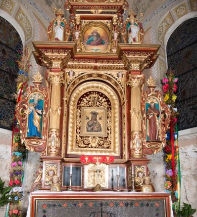 Zdjęcie nr 2: Nastawa ołtarzowa architektoniczna, jednoosiowa, dwukondygnacyjna, na cokole. Ołtarz murowany z kamienną mensą. Na lewym boku ołtarza drewniana wnęka na oleje święte z inskrypcją „OLEA SACRA”. Antepedium w formie leżącego prostokąta w profilowanej ramie, pole kompozycyjne dekorowane dookoła rzędem kolorowych rombów. W polu antepedium znajduje się haftowane koralikami przedstawienie gorejącego serca w koronie cierniowej z zatkniętym u góry krzyżykiem łacińskim. Tabernakulum w formie prostopadłościennej skrzynki. Drzwiczki dwuskrzydłowe, odlewane, w polach przedstawienie wici roślinnej oraz litery alfa i omega. Ściany boczne zdobione kaboszonem i ornamentem małżowinowo-chrząstkowym. Nastawa ustawiona jest na cokole. Pierwsza kondygnacja ujęta parą kolumn. Podpory dźwigają pełne belkowanie wyłamane nad polem środkowym, zamknięte silnie wysuniętym gzymsem. Pole obrazowe w formie arkady z obrazem przedstawiającym Chrzest Chrystusa, na zasuwie obraz Matki Boskiej Nieustającej Pomocy. Kondygnacja ujęta jest uszami z płytkimi niszami dla figur św. Piotra po lewej stronie i św. Pawła po prawej, zwieńczonymi akroterionami utworzonymi z ornamentu małżowinowo-chrząstkowego. Druga kondygnacja ustawiona jest na cokole, ujęta pilastrami hermowymi o kapitelach korynckich, dźwigającymi pełne belkowanie z silnie wystającym gzymsem. Pole obrazowe w formie owalu z przedstawieniem Boga Ojca i Gołębicy Ducha Świętego. Po bokach drugiej kondygnacji znajdują się nisze z figurami św. Stanisława po prawej stronie i nierozpoznanego świętego biskupa po lewej. Ołtarz zwieńczony  jest cokołem z figurą św. Wojciecha.

Cokoły kolumn pierwszej kondygnacji dekorowane są z frontu uskrzydlonymi główkami anielskimi, na zewnętrznych bokach kartuszami z tarczą herbową czteropolową z herbami: Lubicz, Leliwa, Junosza i Rawicz; od wewnątrz ornamentem małżowinowym z chrząstką i kaboszonem. Cokoły kolumn pierwszej kondygnacji w jednej trzeciej wysokości zdobione są ornamentem małżowinowym z kaboszonami, powyżej trzon otoczony jest podwiązaną tkaniną. W polu środkowym w przyłuczach arkady umieszczone są uskrzydlone główki anielskie; węgary od wewnątrz dekorowane są kaboszonami z małżowiną oraz rozetami, podłucze zaś rozetami. Fryz zdobiony jest kaboszonami z małżowiną; a gzyms dekoracją roślinno-geometryczną. Uszy z niszami utworzone są z ornamentu małżowinowo-chrząstkowego. Cokół drugiej kondygnacji dekorowany jest ornamentem małżowinowo-chrząstkowym i kaboszonem, a trzony kolumn utworzone są uskrzydlonych główek anielskich o stylizowanych na woluty skrzydłach. W czterech narożach pola obrazowego umieszczone są uskrzydlone główki anielskie. W polu fryzu znajduje się uskrzydlona główka anielska; gzyms dekorowany jest ornamentem roślinnym. Kondygnacja ujęta jest uszami z płaskiej małżowiny. Gzyms zakończony ażurowym ornamentem małżowinowo-chrząstkowym. Nisze z figurami otoczone są ornamentem małżowinowo-chrząstkowym i zwieńczone cokołami z palmetą. 
Nastawa polichromowana na czerwono z zielonymi i czarnymi elementami. Ornamentyka i kolumny złocone, kaboszony srebrzone.