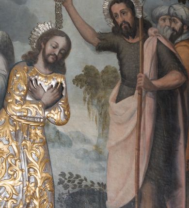 Zdjęcie nr 3: Obraz w formie stojącego prostokąta zamkniętego łukiem półkolistym. W centrum postać Chrystusa zwróconego trzy czwarte w lewo, delikatnie pochylonego z dłońmi skrzyżowanymi na piersi. Twarz owalna o wyraźnych rysach, półprzymkniętych oczach, okolona zarostem. Włosy długie, w postaci loków opadają na ramiona. Chrystus w drewnianej sukience z  płaskorzeźbionym motywem akantu i kwiatów. Po prawej stronie św. Jan Chrzciciel  zwrócony delikatnie w prawo. W lewej ręce trzyma krzyż, u góry obwiedziony banderolą z napisem „AGNVS DEI”, prawą unosi nad głową Jezusa, w dłoni ma płaskorzeźbioną muszelkę, z której wypływa woda. Twarz szczupła, okolona zarostem, z wyraźnie zaznaczonymi kośćmi policzkowymi, włosy ciemne i długie. Ubrany jest w melotę i jasnoróżowy płaszcz. W lewej części obrazu, za Chrystusem dwaj aniołowie. Za św. Janem dwaj mężczyźni w turbanach na głowach. Scena na tle krajobrazu z rzeką. W górnej części płaskorzeźbiona gołębica Ducha Świętego z nałożoną srebrną sukienką. Nad głowami Chrystusa i św. Jana Chrzciciela promieniste, półkoliste nimby ze srebrnej blachy. Kolorystyka jasna i pastelowa. 