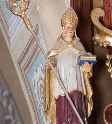 Zdjęcie nr 9: Ołtarz architektoniczny, jednoosiowy, jednokondygnacyjny ze zwieńczeniem. Ołtarz murowany, prostopadłościenny z kamienną mensą. Antepedium drewniane, w polu którego ozdobny, płaskorzeźbiony monogram Chrystusa na niebieskim tle wraz z dekoracją ornamentalną w narożach pola. Pole ujęte ozdobną ramą z płaskorzeźbionym ornamentem z wici roślinnej na jasnoniebieskim tle. Drewniane retabulum ustawione na cokole. W polu obraz z przedstawieniem Modlitwy w Ogrójcu w kształcie leżącego prostokąta o krótszych bokach zakończonych łukiem nadwieszonym. Nastawa flankowana parą kolumn podtrzymujących wyłamane nad osią główną belkowanie. W polu głównym obraz Ecce Homo, a na zasuwie obraz św. Antoniego Padewskiego. Zwieńczenie w formie owalu ujętego ażurową dekoracją formowaną z ornamentu małżowinowo-chrząstkowego na tle kwadratowej ramy. W polu obraz Chrystusa u słupa, po bokach figury, po lewej św. Mikołaja, po prawej św. Doroty, na szczycie figura św. Józefa. Partie cokołów ozdobione płycinami z uskrzydlonymi główkami aniołów w polu, po bokach dekorowane ornamentem małżowinowo-chrząstkowym. Zasadnicza część nastawy ujęta po bokach uszami z ornamentem o formach małżowinowo-chrząstkowych, z czego prawy złożony, dostosowany do południowego filaru kościoła. Trzony kolumn w dolnej partii ozdobione kartuszami o fantazyjnych wycięciach z motywami kaboszonów, w górnej partii pokryte dekoracją w formie wici winnej latorośli. W partii fryzu oraz pod gzymsem ornamentyka roślinna. Pośrodku belkowania motyw dekoracyjnego spływu z uskrzydloną główką aniołka z podwiązaną chustą pod szyją. Pole środkowe w formie prostokątnej wnęki ujętej profilowanymi ramami z czego wewnętrzna ozdobiona ornamentem małżowinowo-chrząstkowym. Polichromia struktury ołtarza utrzymana w odcieniach ciemnego brązu i czerwieni, partie w tle ornamentów niebieskie. Ornamentyka i elementy detalu architektonicznego złocone i srebrzone. 

